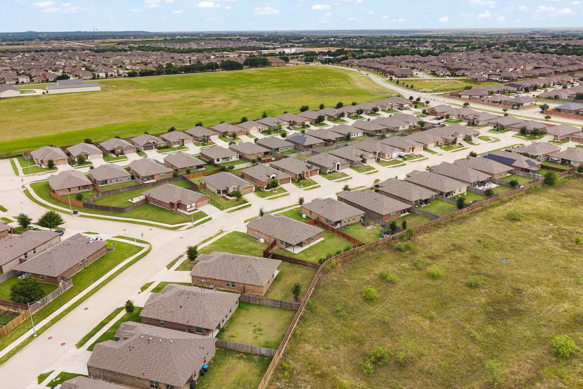 Expansive residential development featuring numerous single-story homes with brown shingle roofs