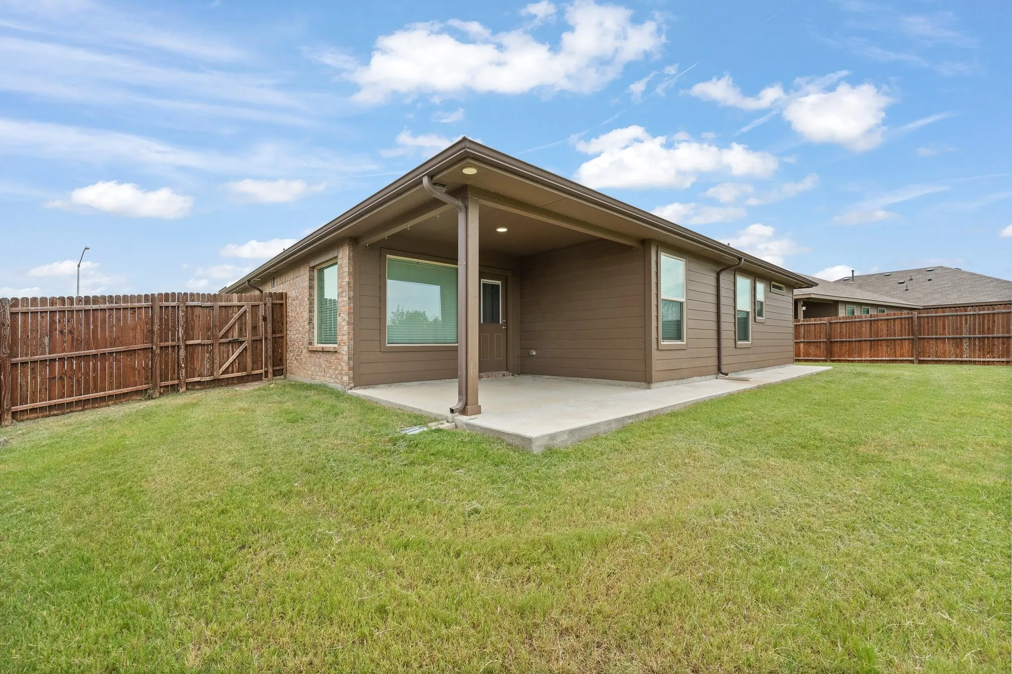Expansive backyard featuring a covered patio, a manicured lawn, and a wood privacy fence