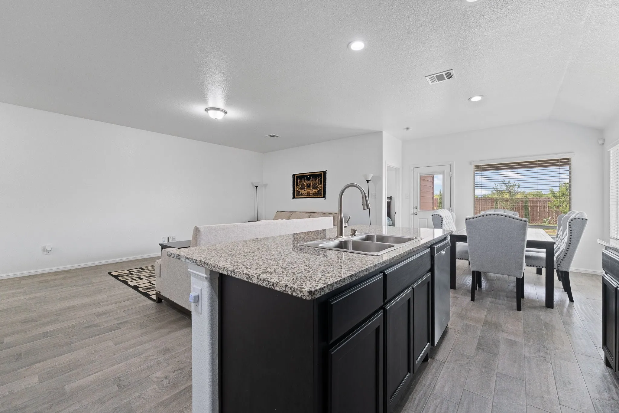 Kitchen island featuring a double basin sink and a high-arc faucet, set against wood-finish flooring