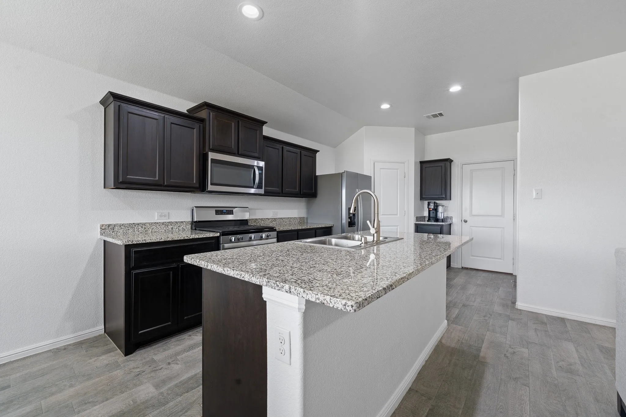 Kitchen island featuring a double basin sink and a high-arc faucet, complemented by granite countertops