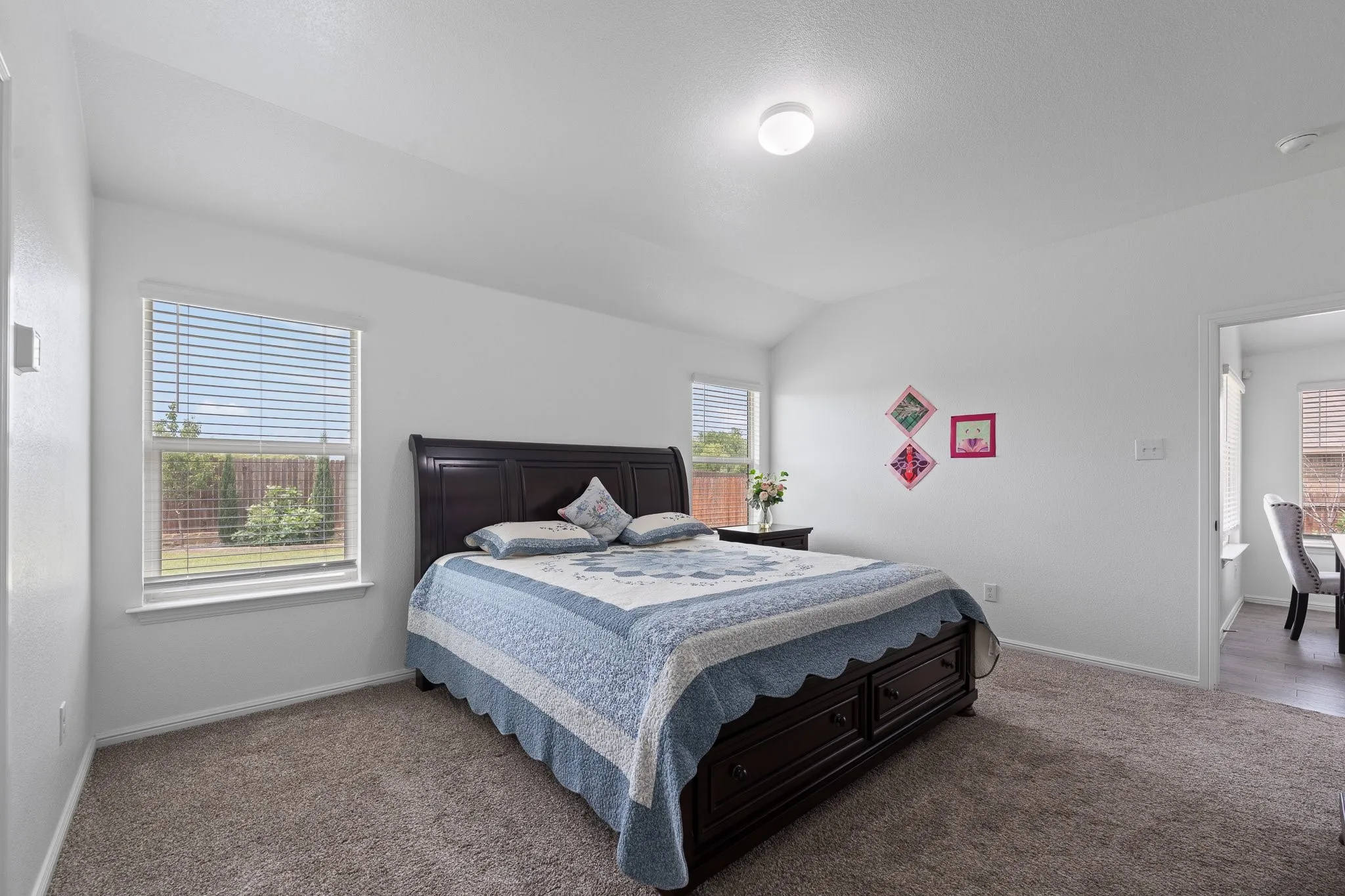 Carpeted room with vaulted ceiling and two windows