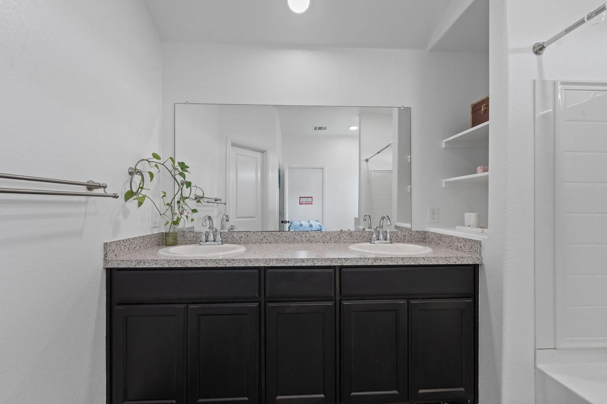Dual vanity with dark wood-finish cabinetry and light speckled countertops