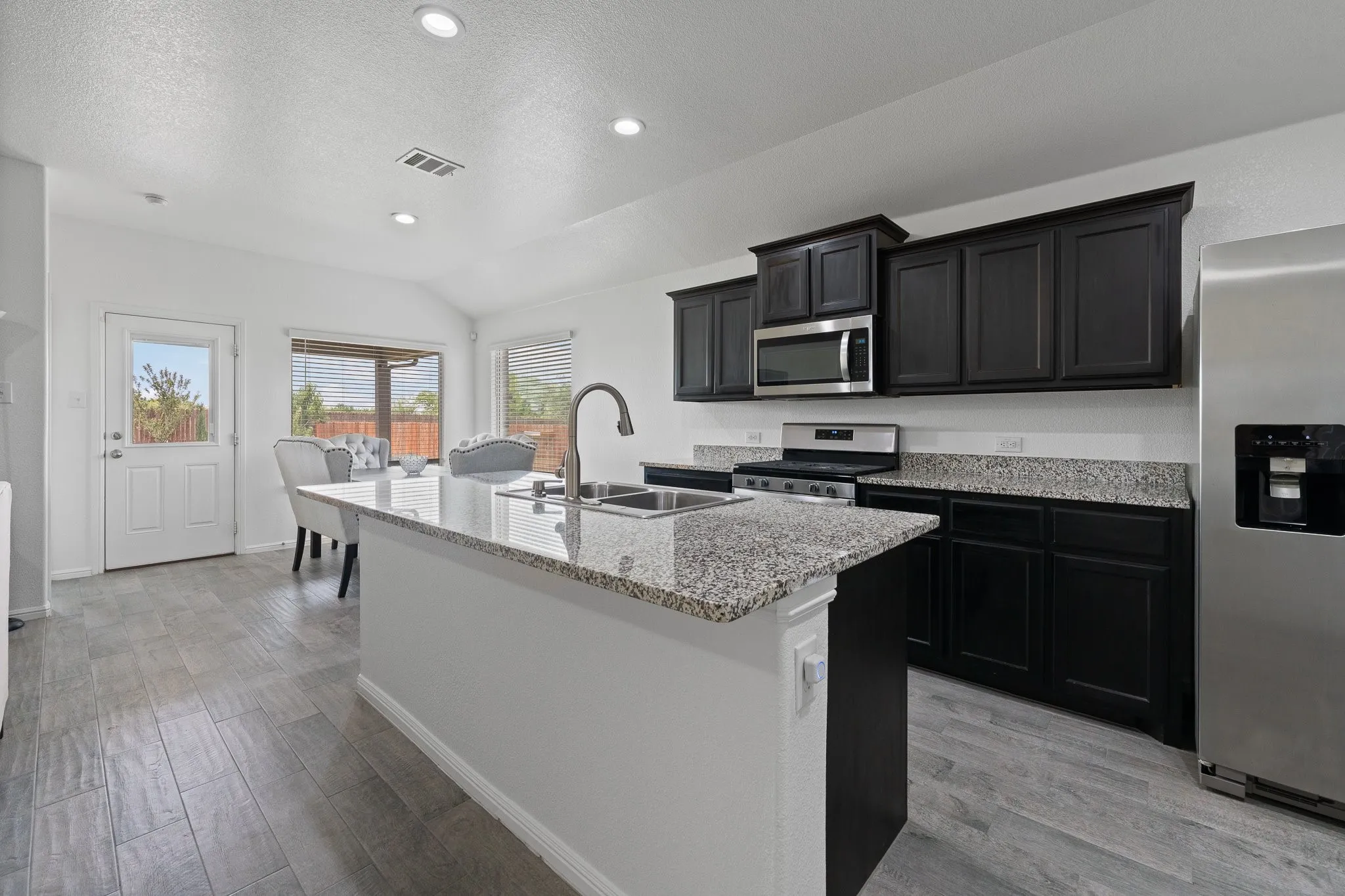 Kitchen featuring a central island with a double basin sink and a gooseneck faucet