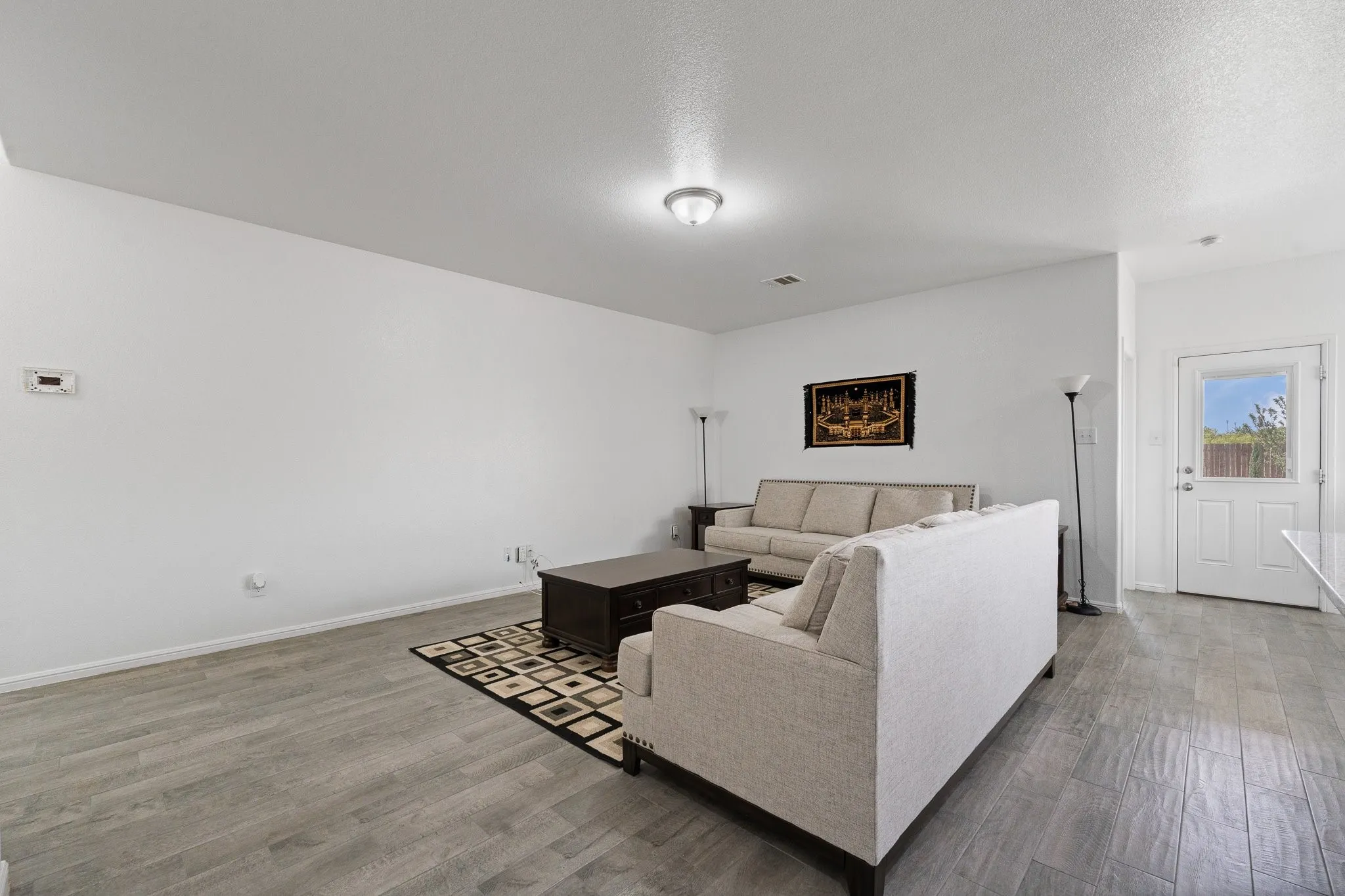 Spacious room featuring wood-finish flooring, recessed lighting, and a white paneled door with window