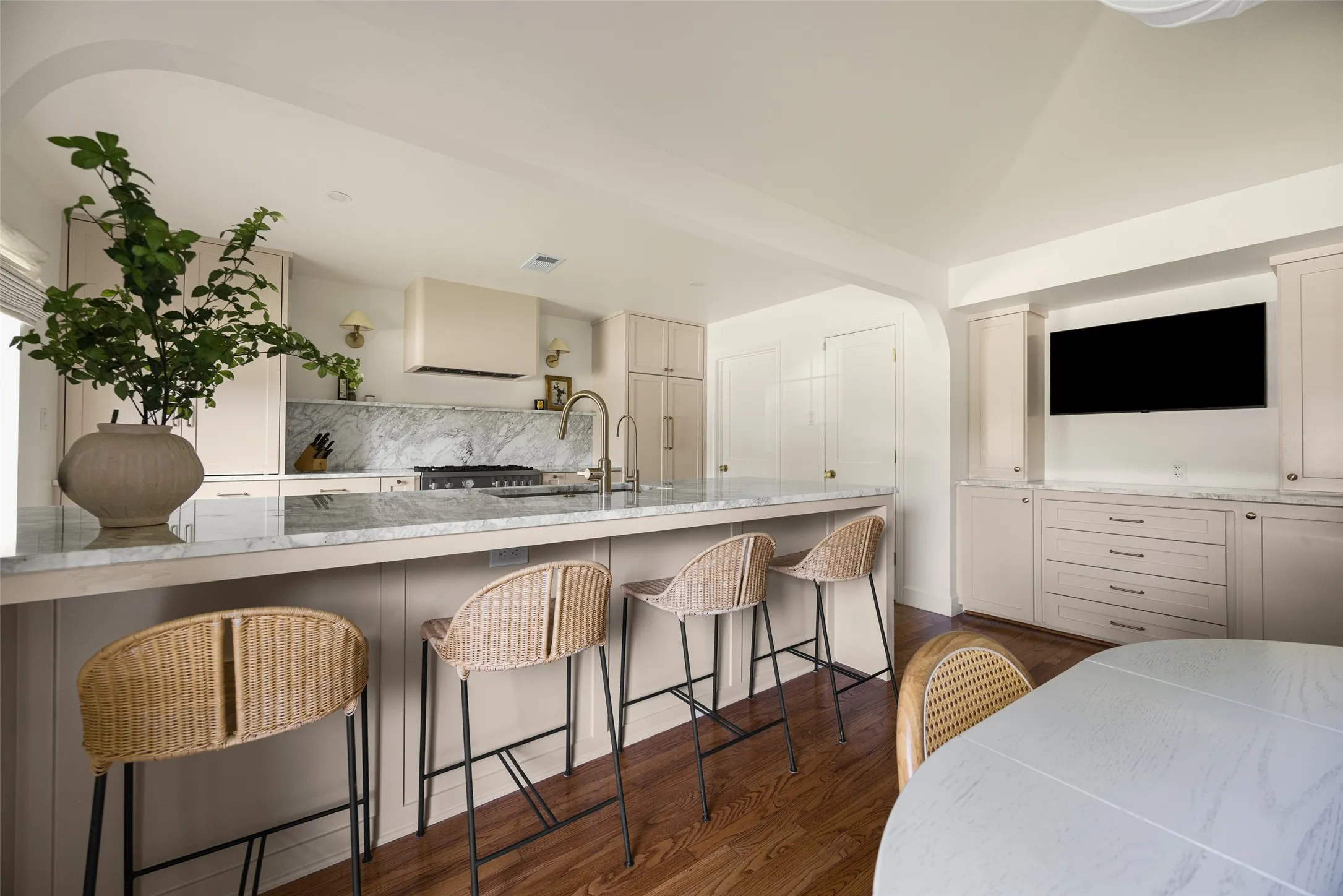 Kitchen featuring a large central island with seating, a built-in range, a marble backsplash, and ample cabinetry