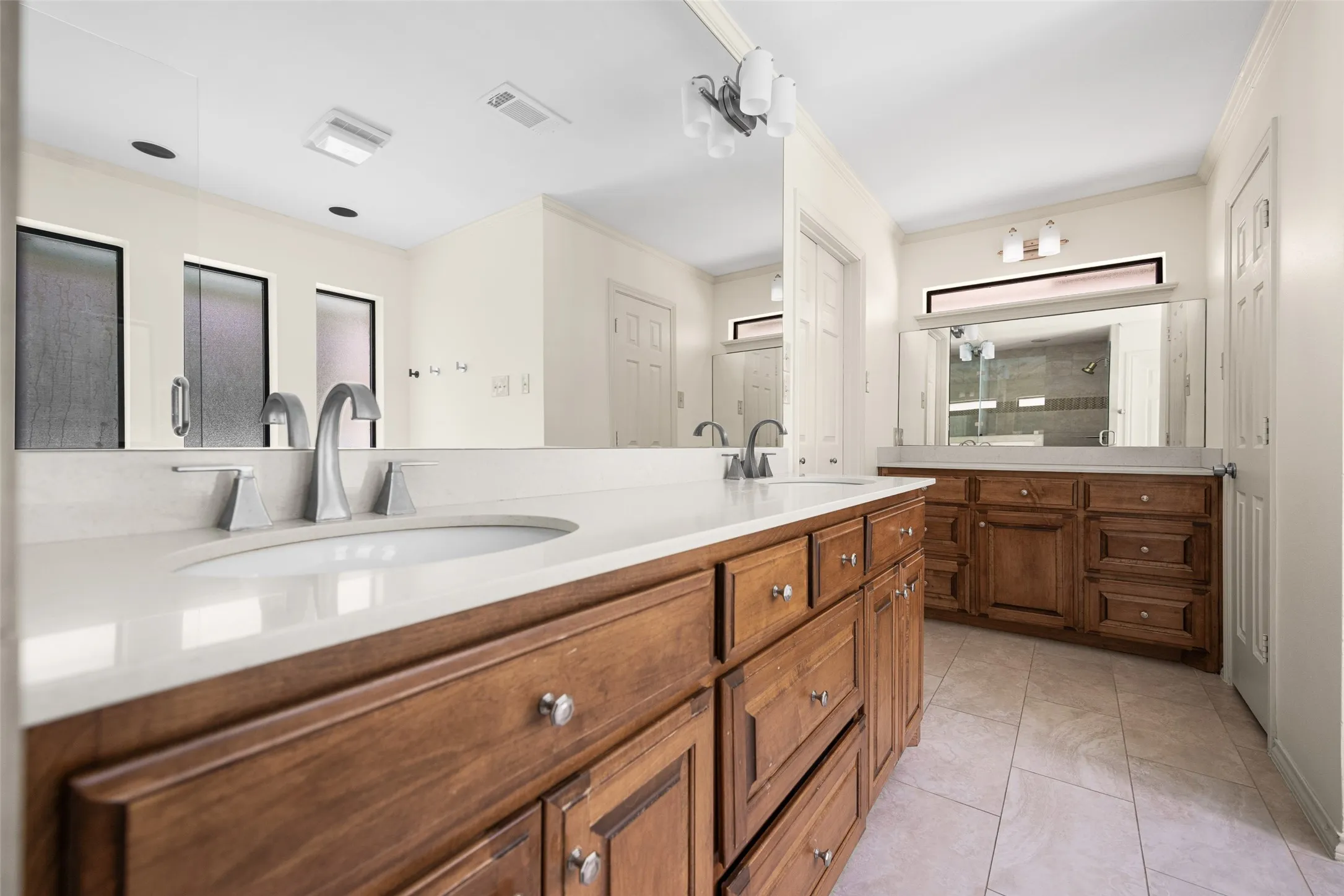 Double vanity featuring wood cabinetry, white stone countertops, and undermount sinks