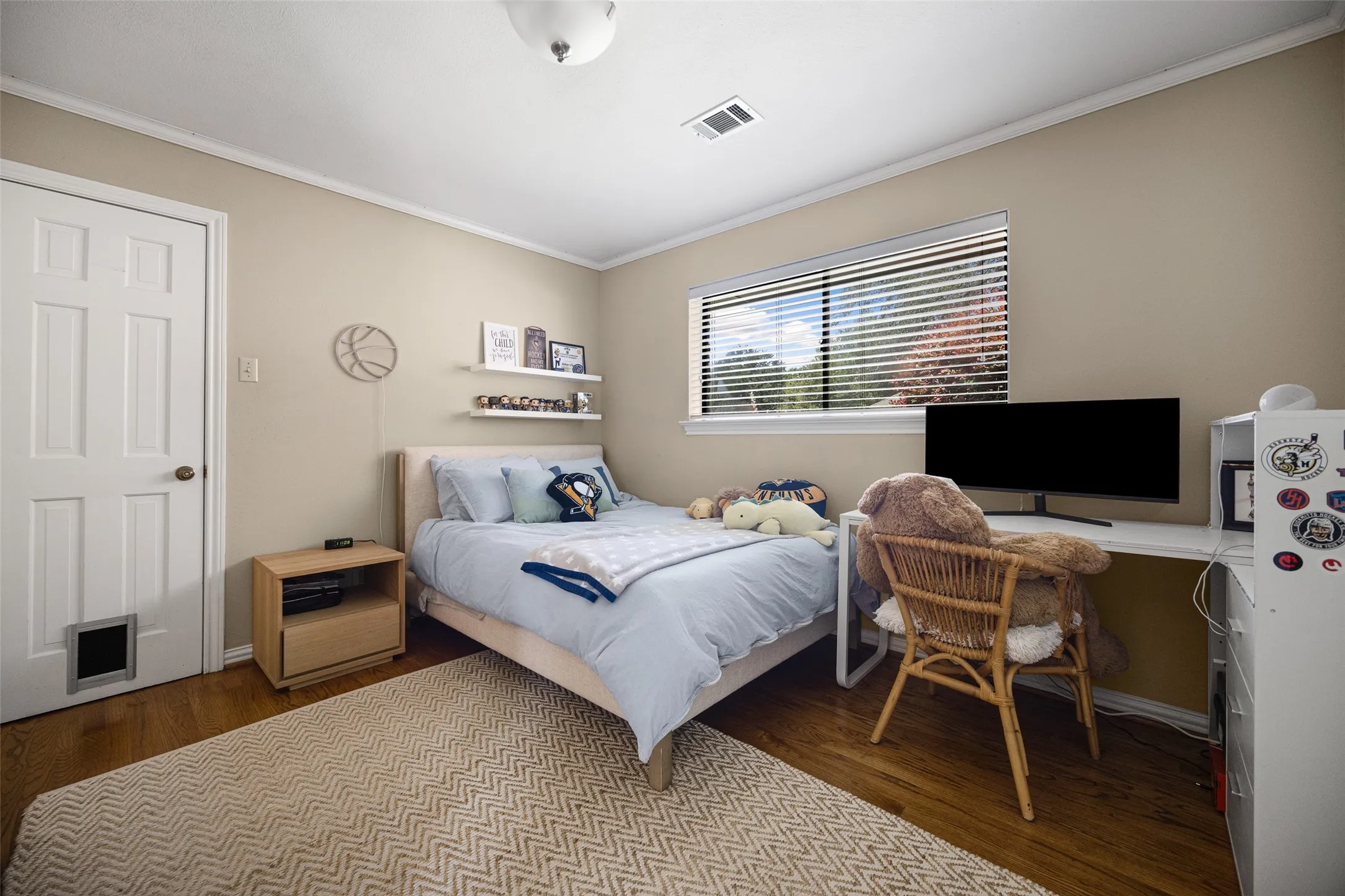 Bedroom featuring wood-finish flooring, a six-panel door, and a window with blinds