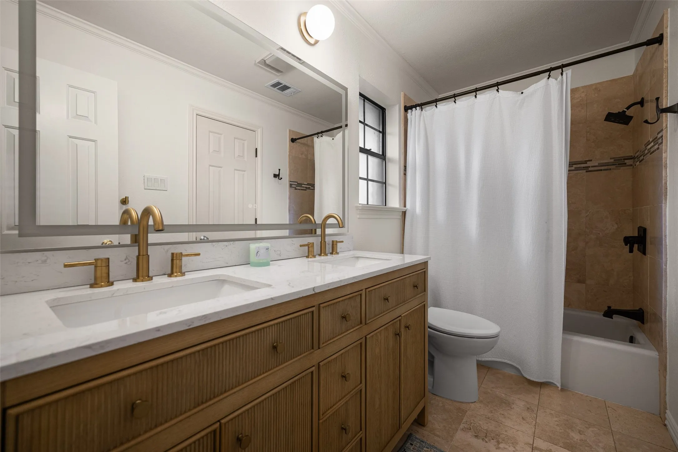 Bathroom featuring a double vanity with gold-tone fixtures, a white countertop, and integrated sinks