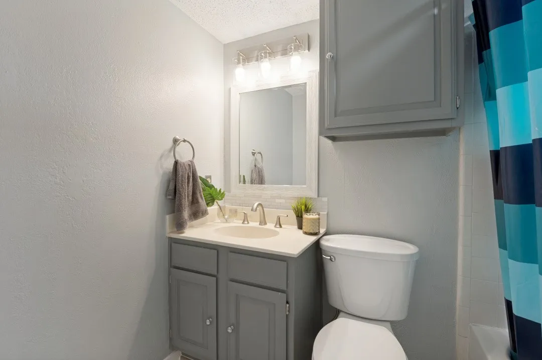 Vanity with an integrated sink, brushed nickel faucet, and a framed mirror with overhead lighting