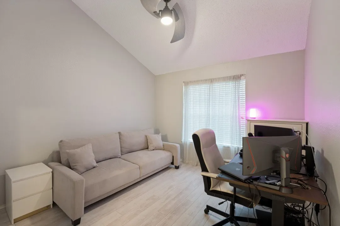 Sloped ceiling with an attached ceiling fan, light-toned walls, and wood-finish flooring