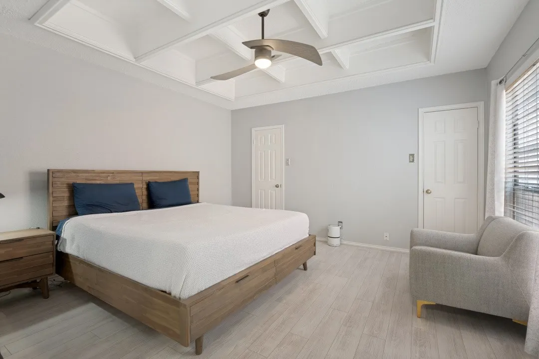 Coffered ceiling with a ceiling fan, light wood-finish flooring, and white paneled doors
