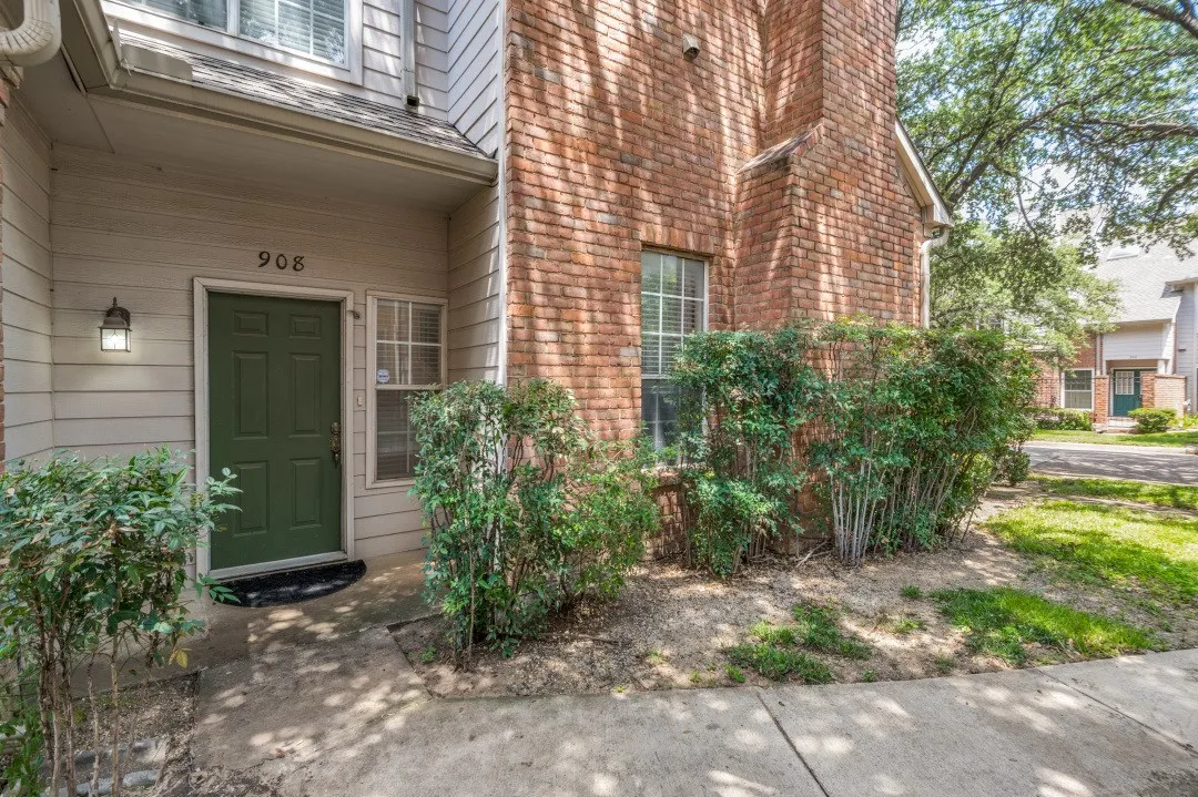 Welcoming entry featuring a dark green paneled door with sidelights, complemented by brick exterior and mature landscaping