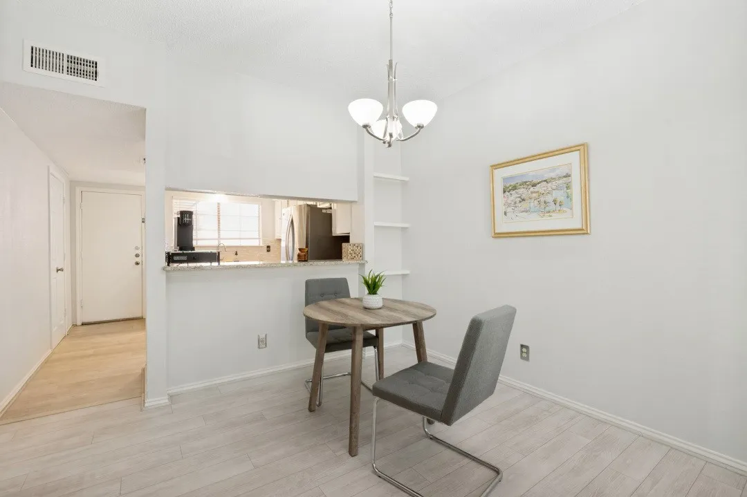 Dining area featuring wood-finish flooring, a contemporary chandelier, and built-in shelving