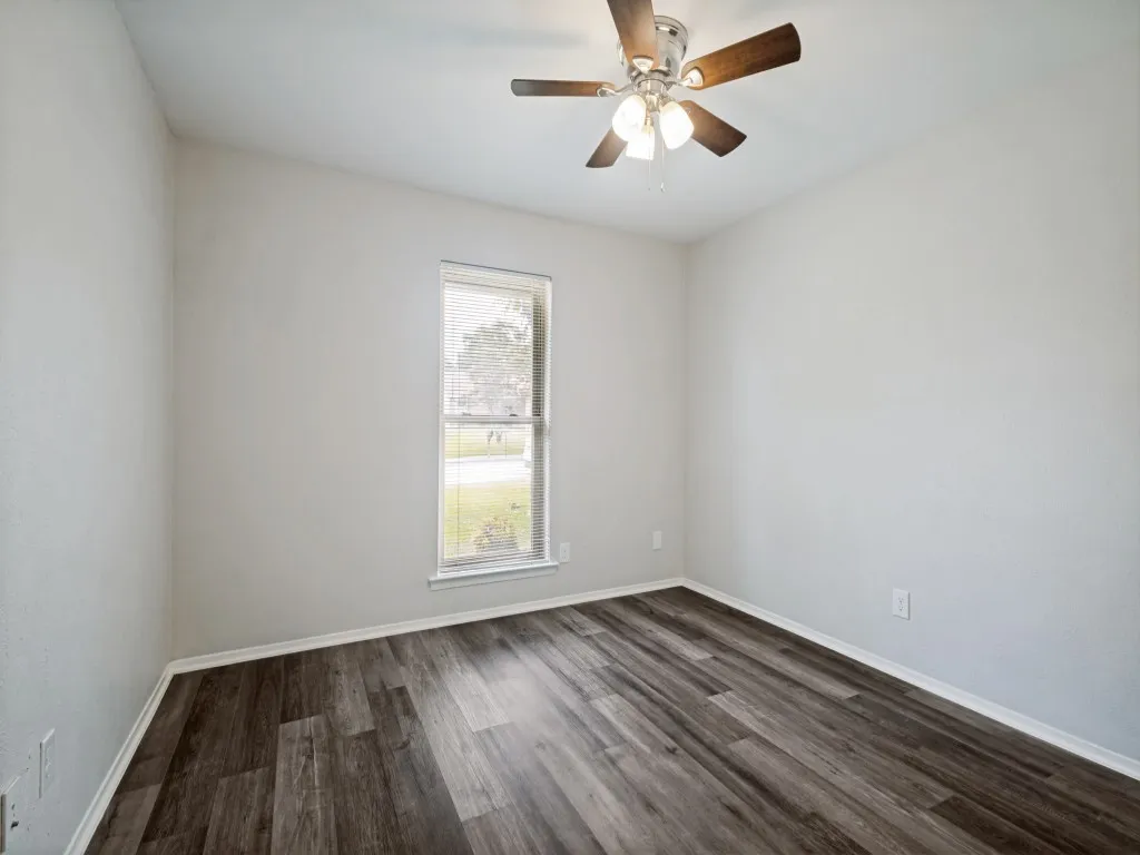 Bright room with wood-finish flooring, white walls, and a window with blinds
