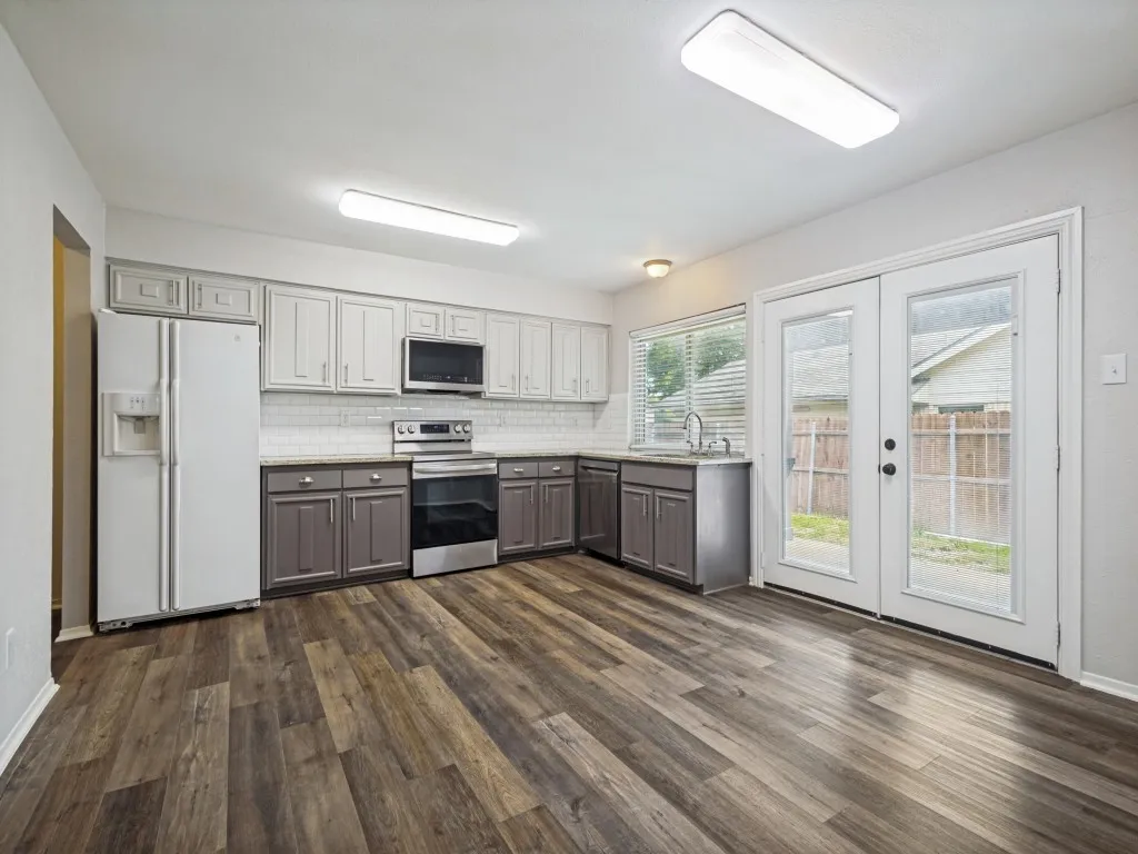 Kitchen featuring two-tone cabinetry, wood-finish flooring, white subway tile backsplash, stainless steel appliances, and double glass doors