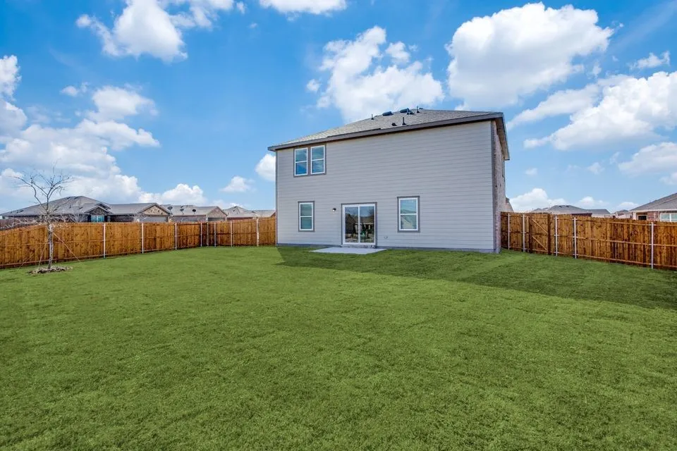 Expansive rear yard featuring a privacy fence, a concrete patio, and a two-story exterior with siding