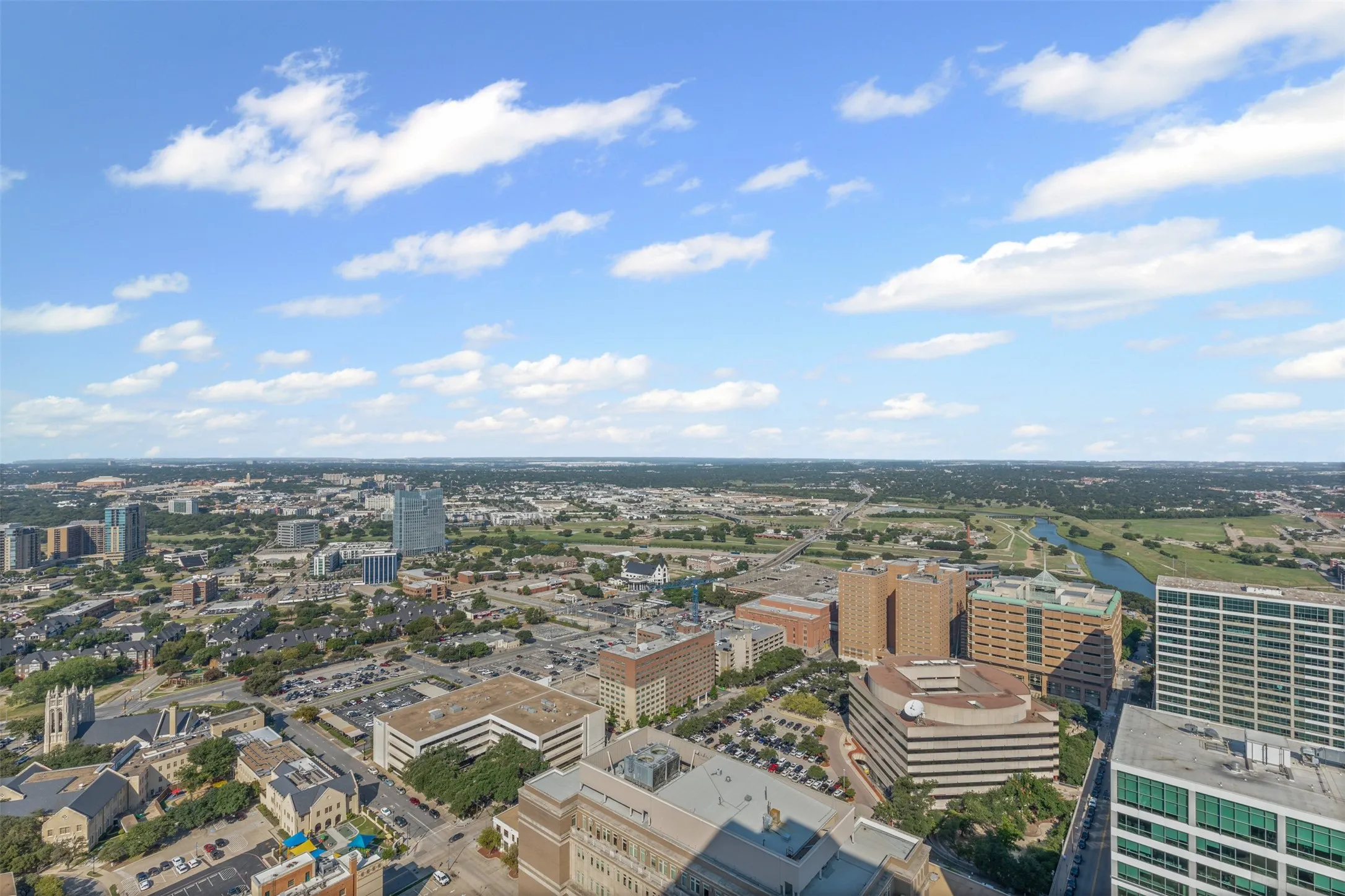 Expansive cityscape panorama featuring diverse architectural styles, a meandering river, and verdant green spaces