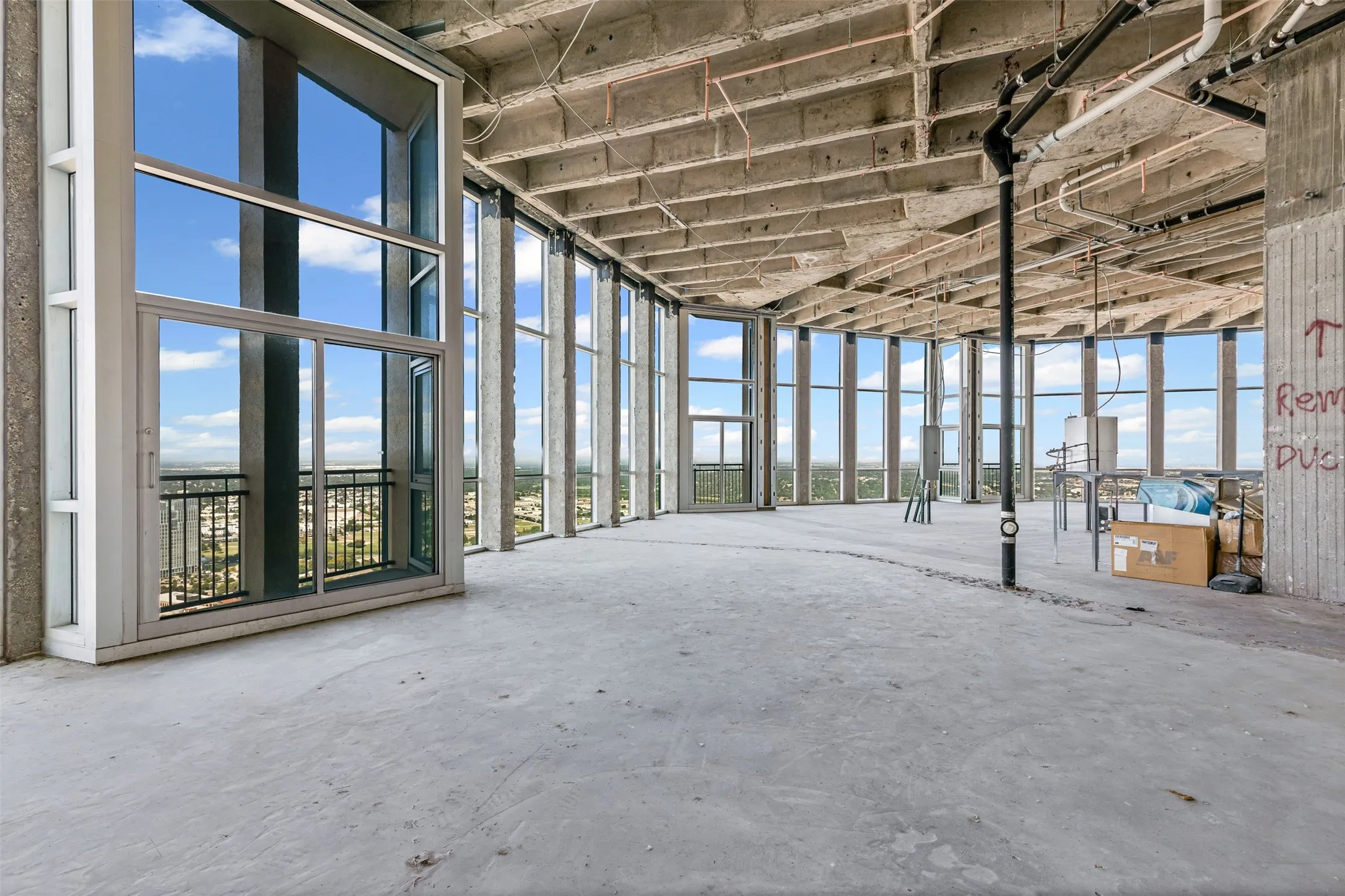 Expansive unfinished interior space featuring concrete flooring and exposed concrete ceilings
