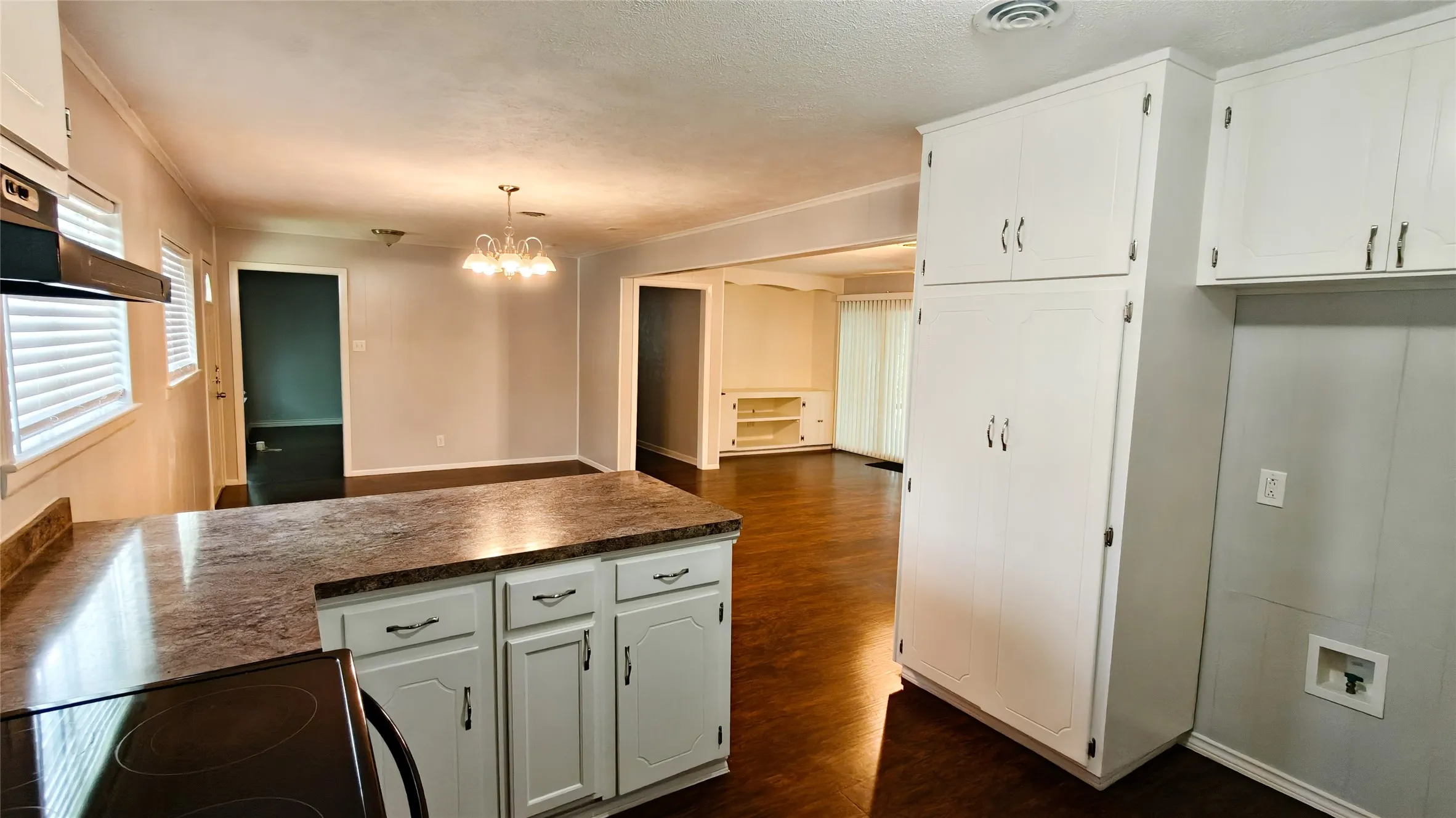Kitchen featuring an integrated electric range, white cabinetry, a patterned countertop, and wood-finish flooring