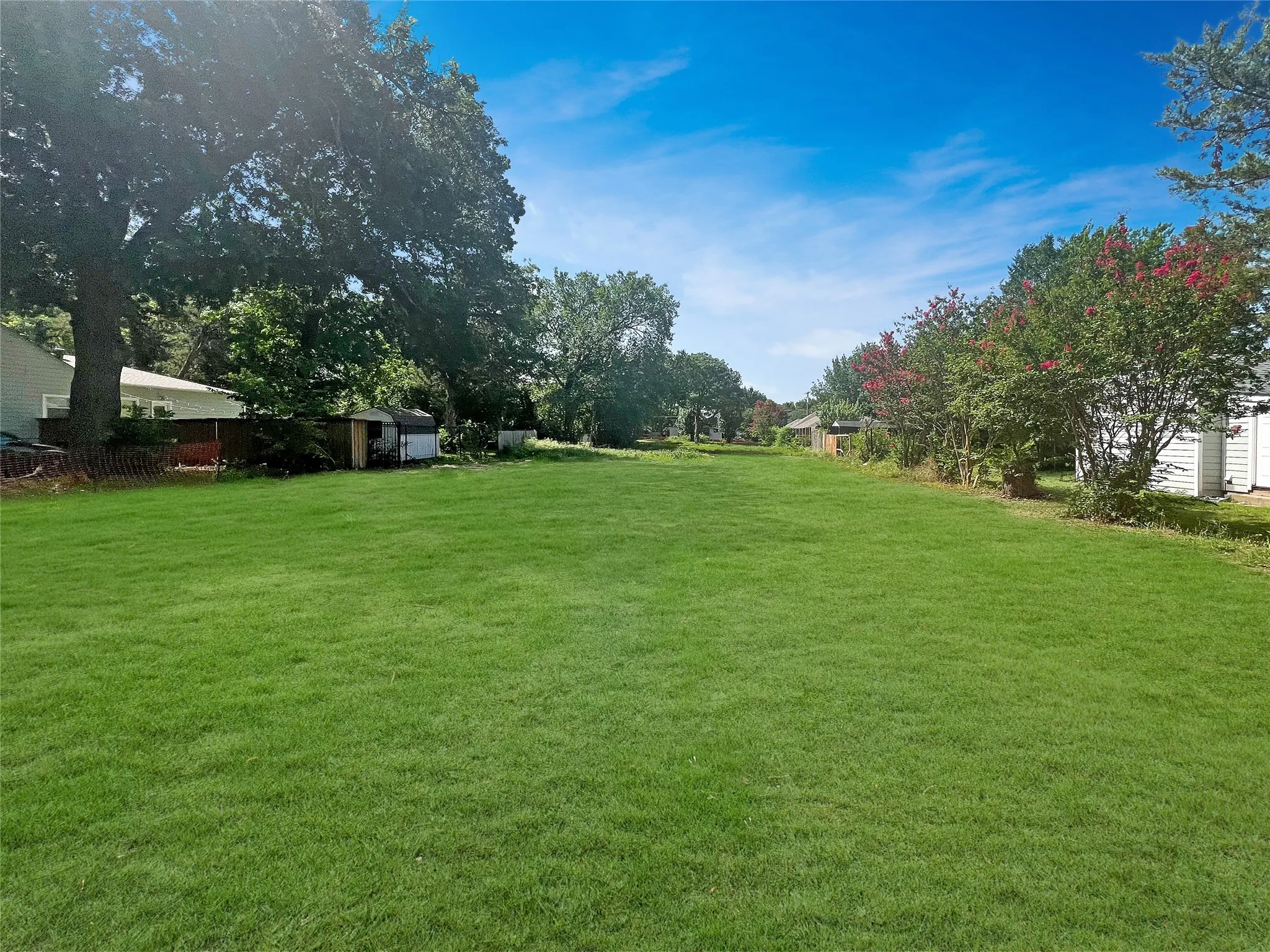 Expansive green lawn with mature trees and established perimeter landscaping