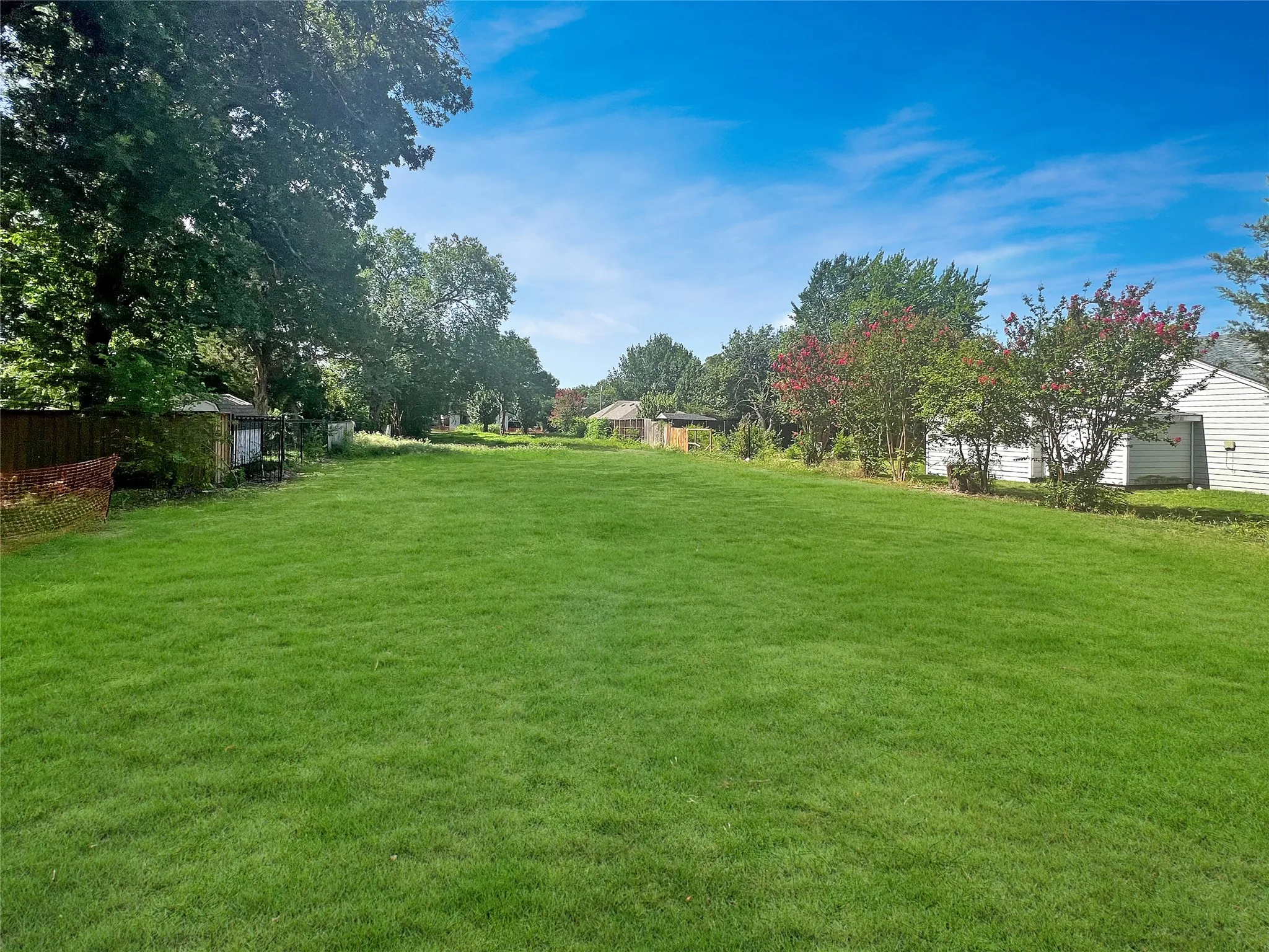 Expansive green lawn with mature trees and perimeter fencing