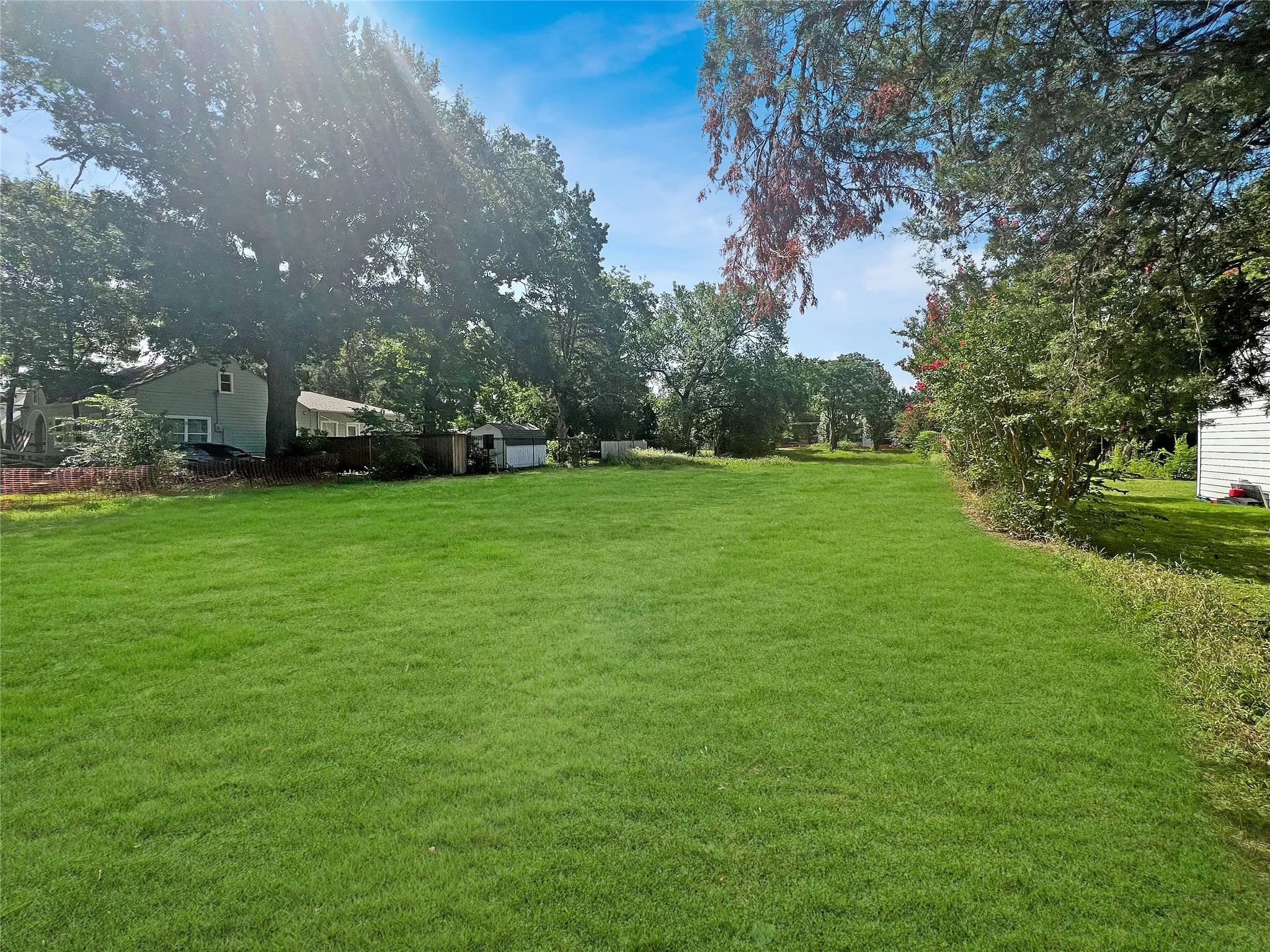 Expansive green lawn with mature trees bordering the property