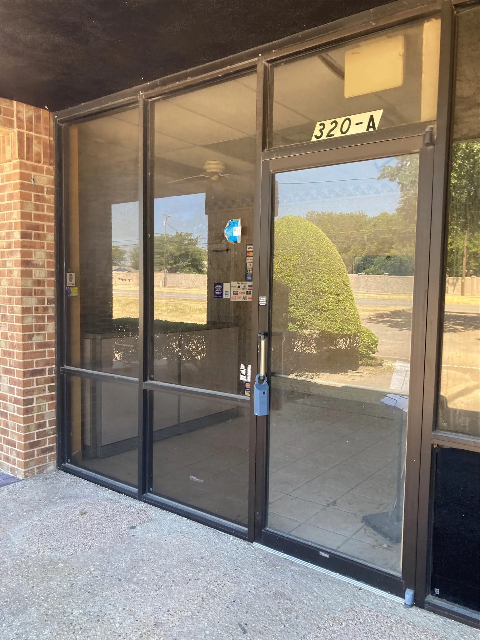 Commercial storefront entrance featuring large glass panels, a brick exterior wall, and a concrete approach