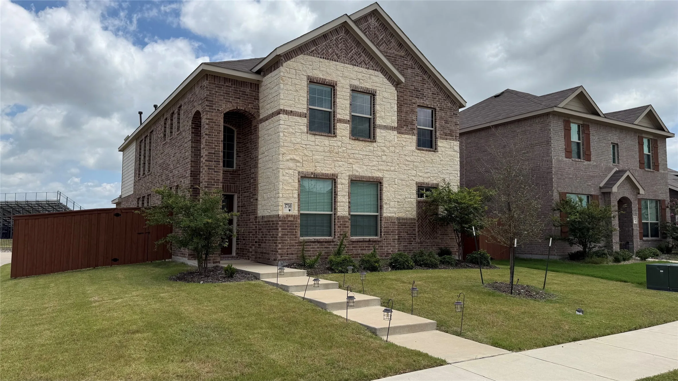 Two-story brick and stone exterior with architectural shingles