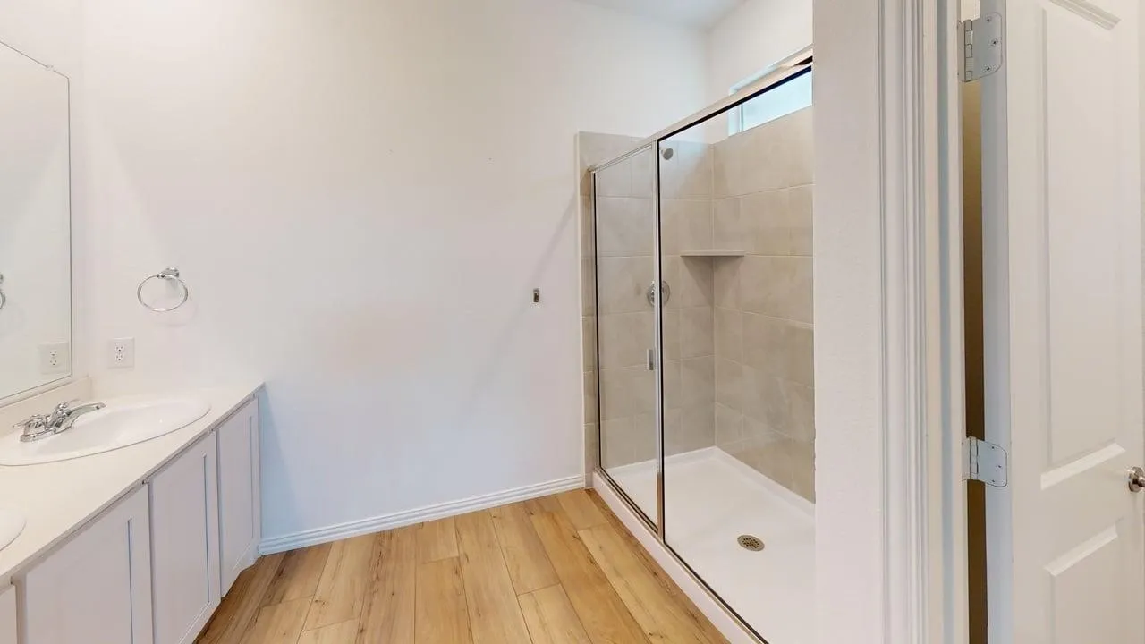 Bathroom featuring a frameless glass shower enclosure with tiled walls and a recessed niche