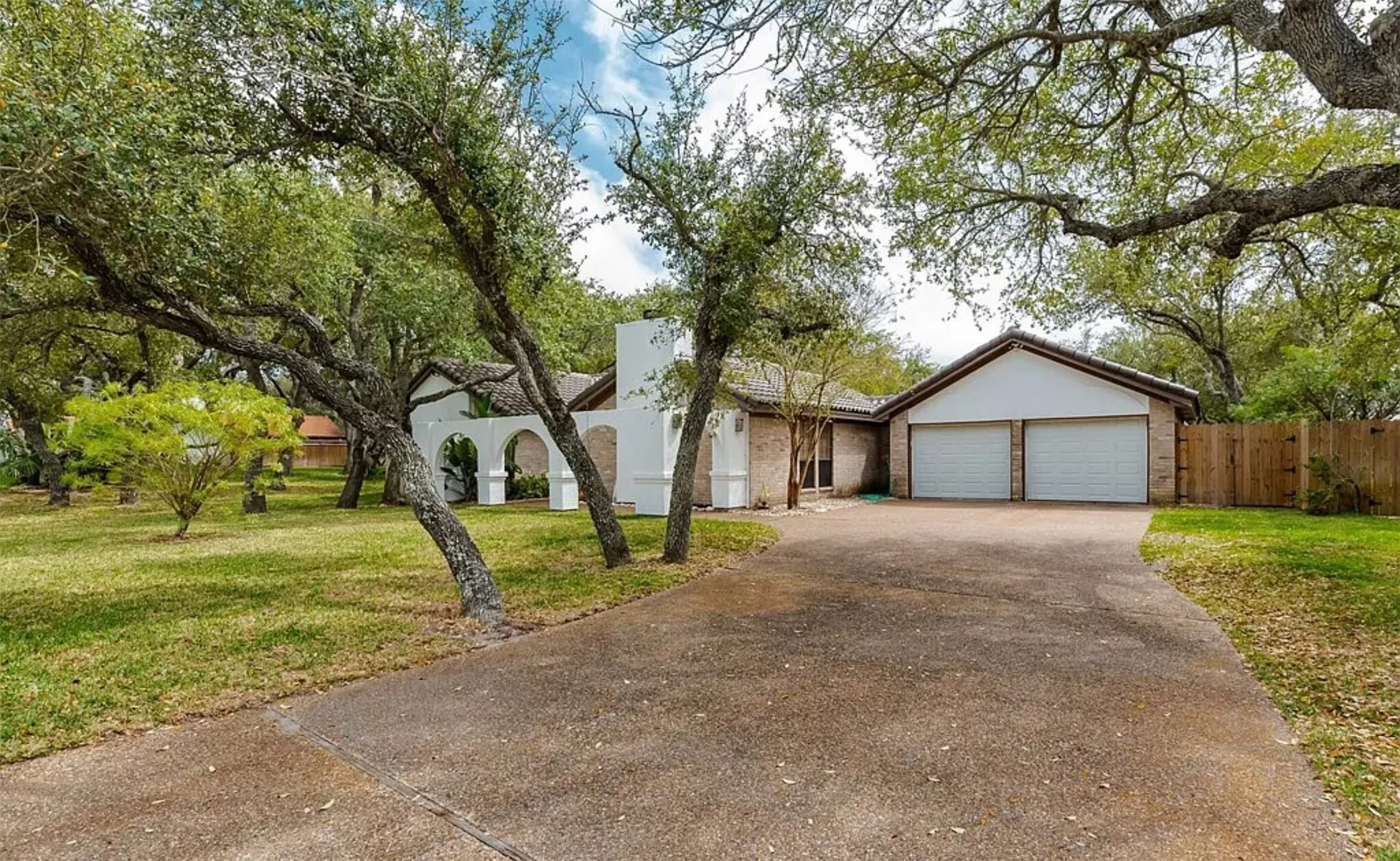 Exterior featuring a two-car garage, concrete driveway, and mature landscaping
