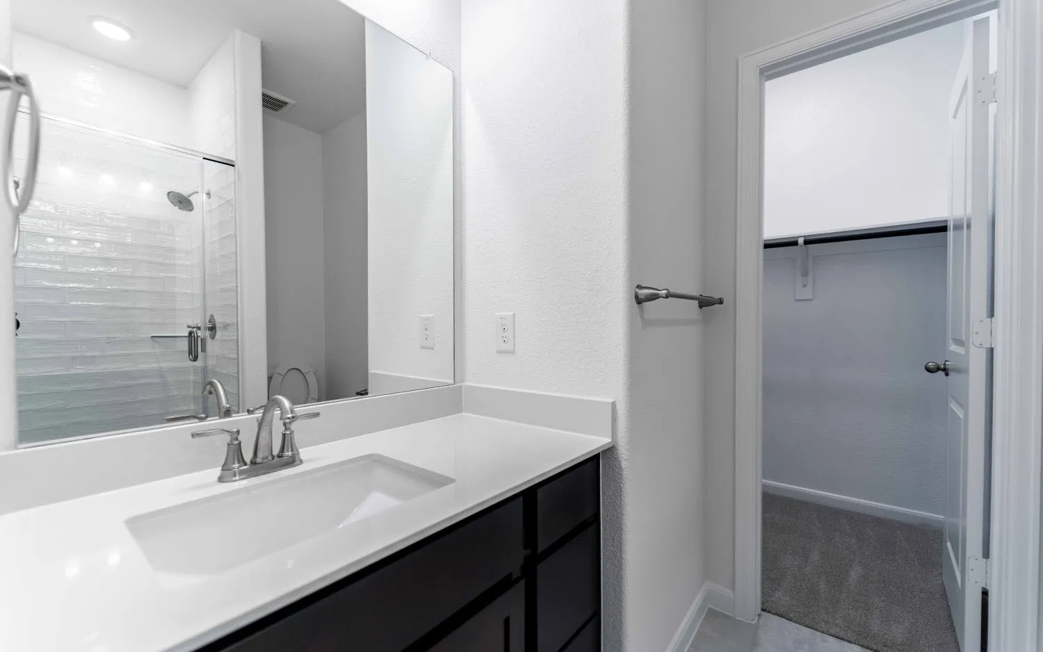 Bathroom vanity featuring a single integrated sink, a dark wood-finish cabinet with drawer storage, and a large mirror