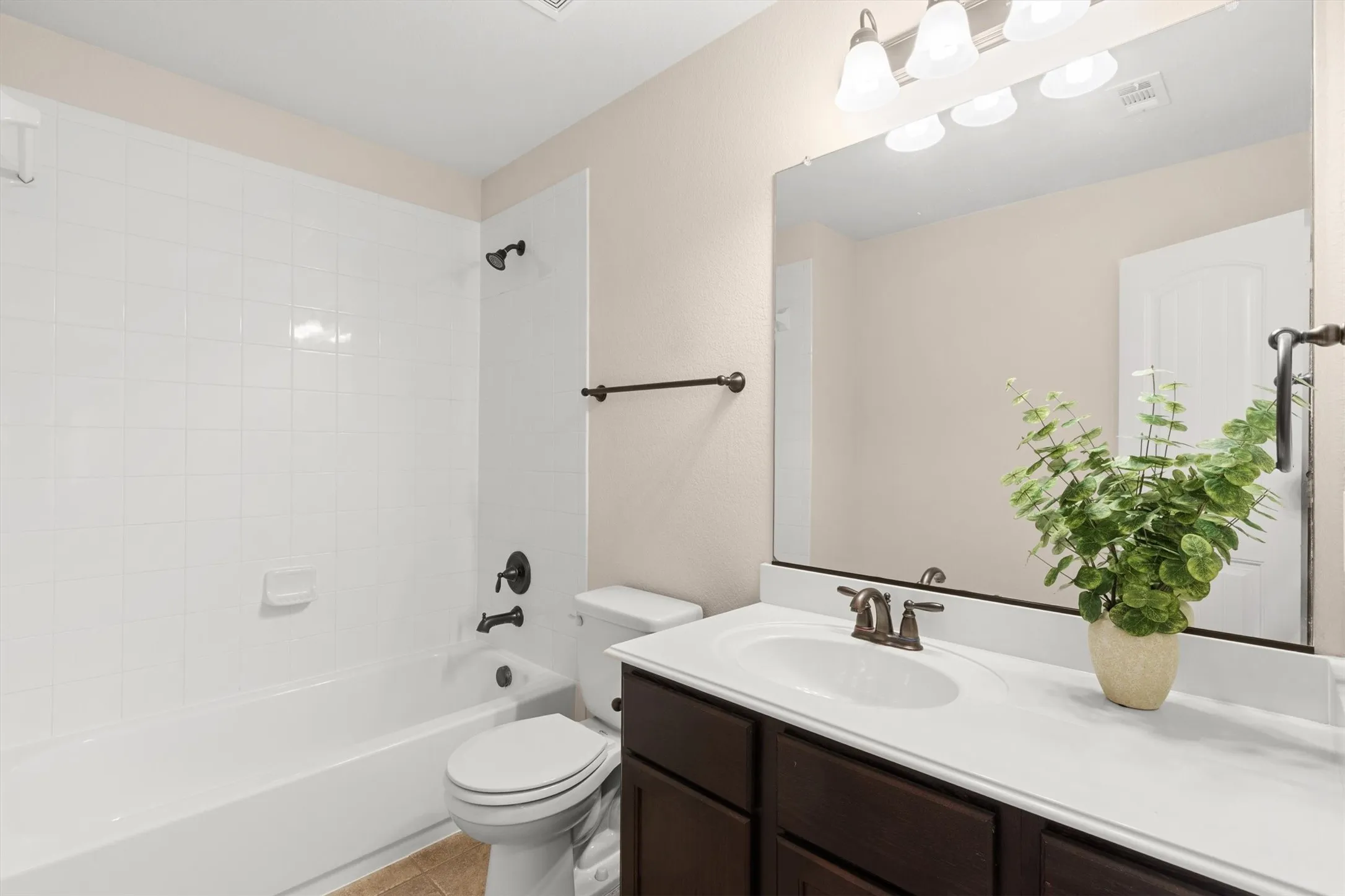 Bathroom featuring a dark wood-finish vanity with an integrated sink, a white countertop, and a large wall-mounted mirror