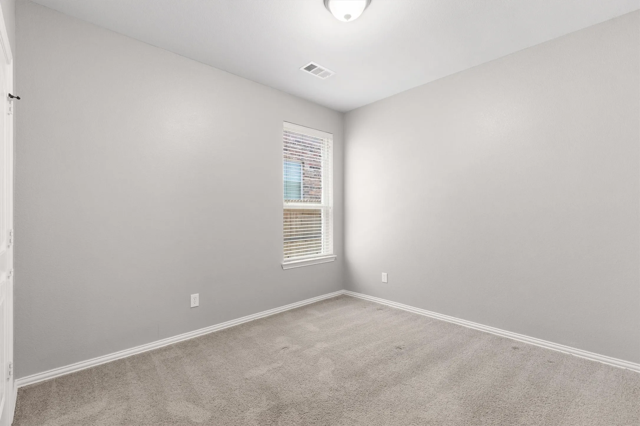 Neutral tone wall paint with white trim, gray carpet, and a white window frame with blinds