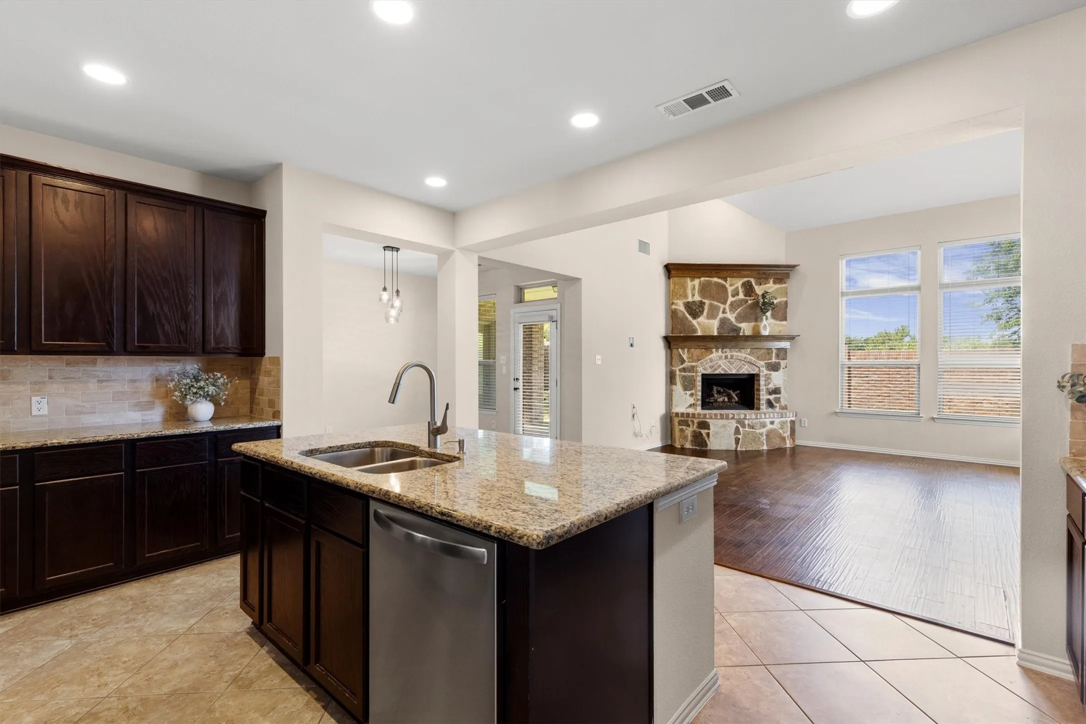 Kitchen island featuring a double basin sink, gooseneck faucet, and stainless steel dishwasher