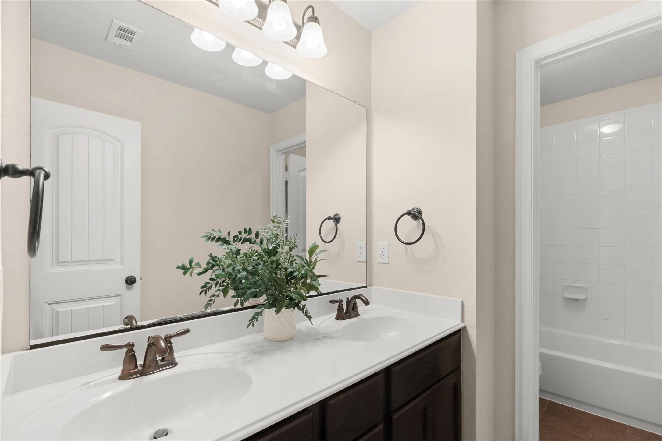 Bathroom featuring a double vanity with white countertops, integrated sinks, and bronze-finish fixtures