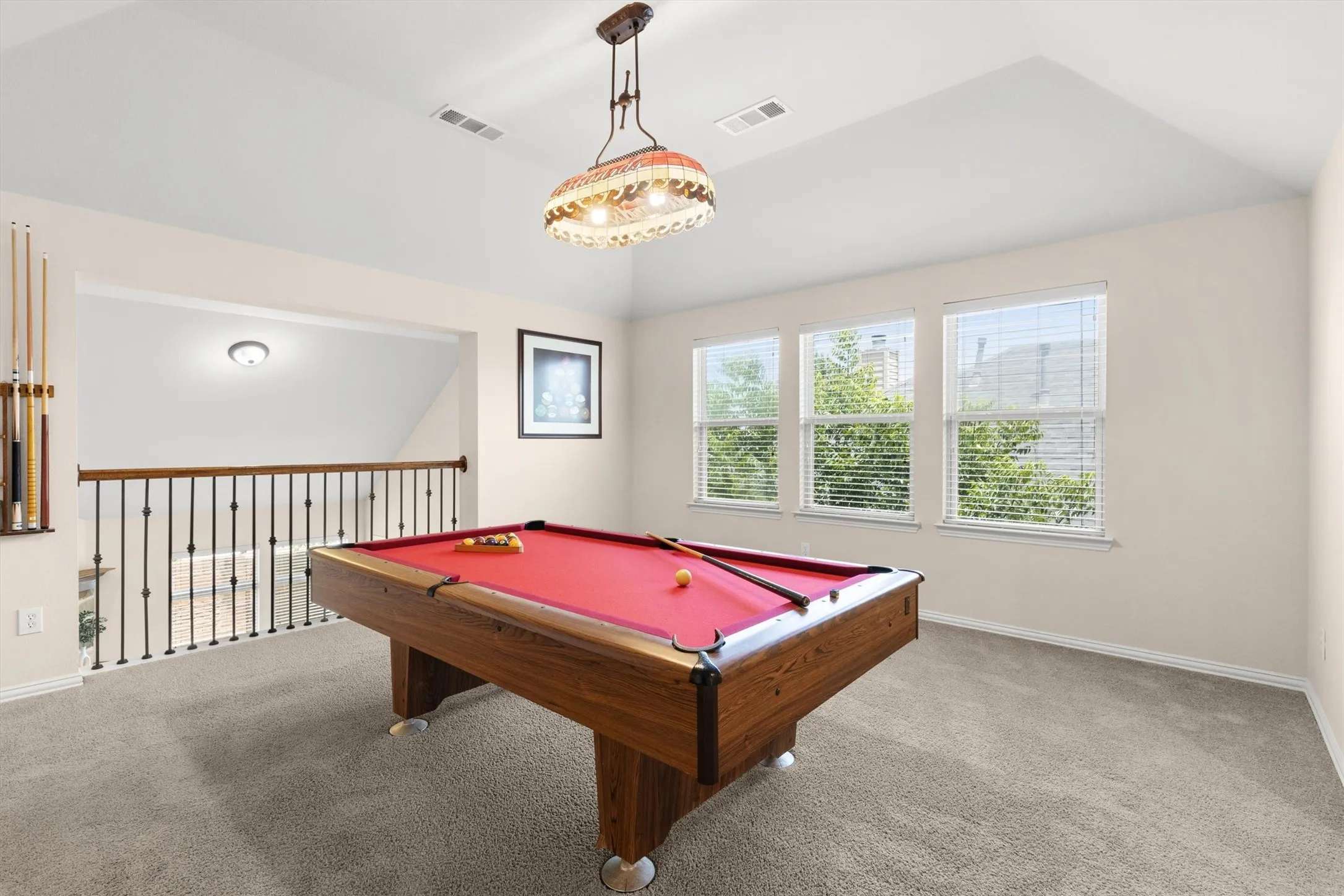 Spacious bonus room featuring vaulted ceilings, plush carpet flooring, and three large windows
