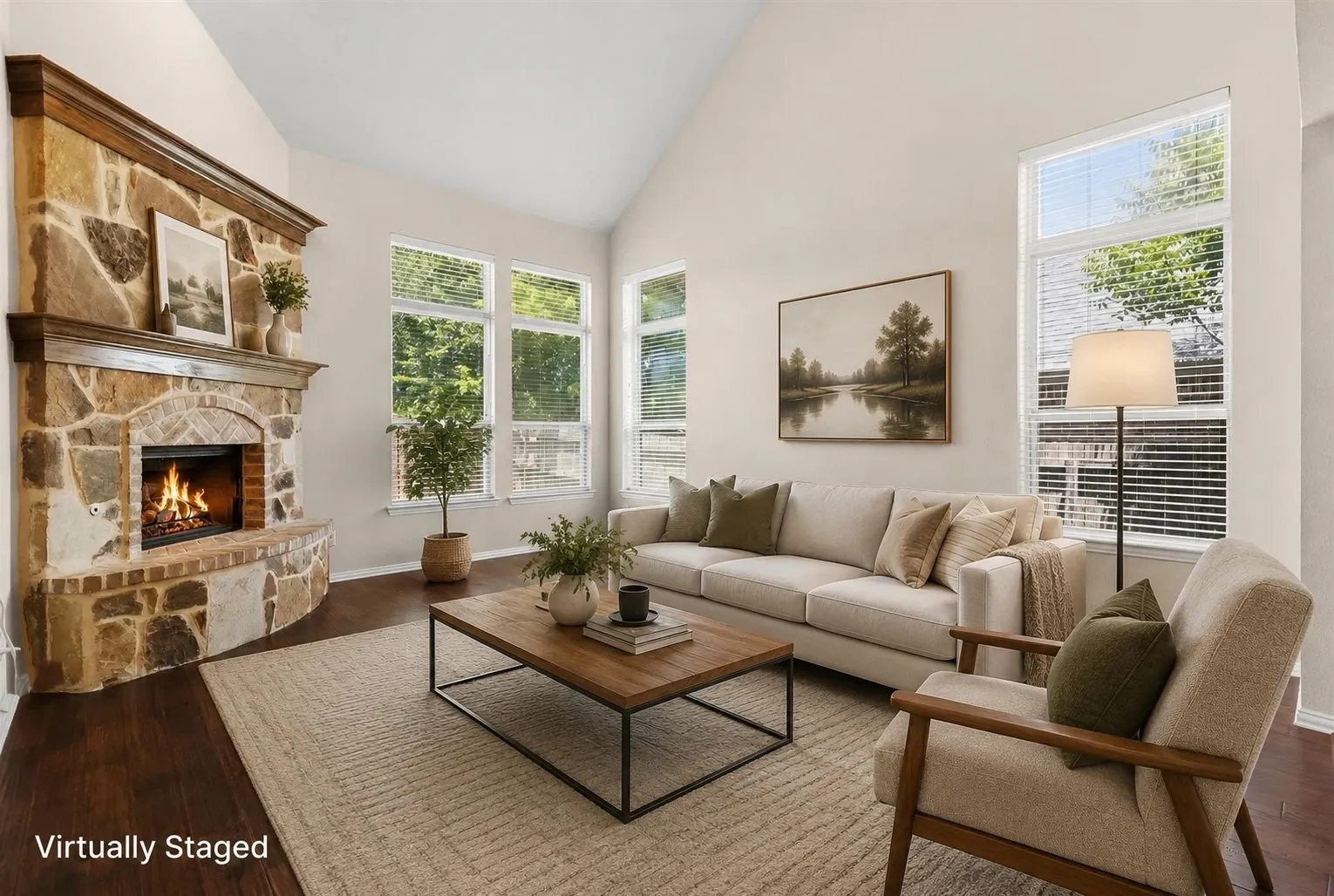 Vaulted ceilings, a stone-clad fireplace with a wood mantle, multiple tall windows, and wood-finish flooring