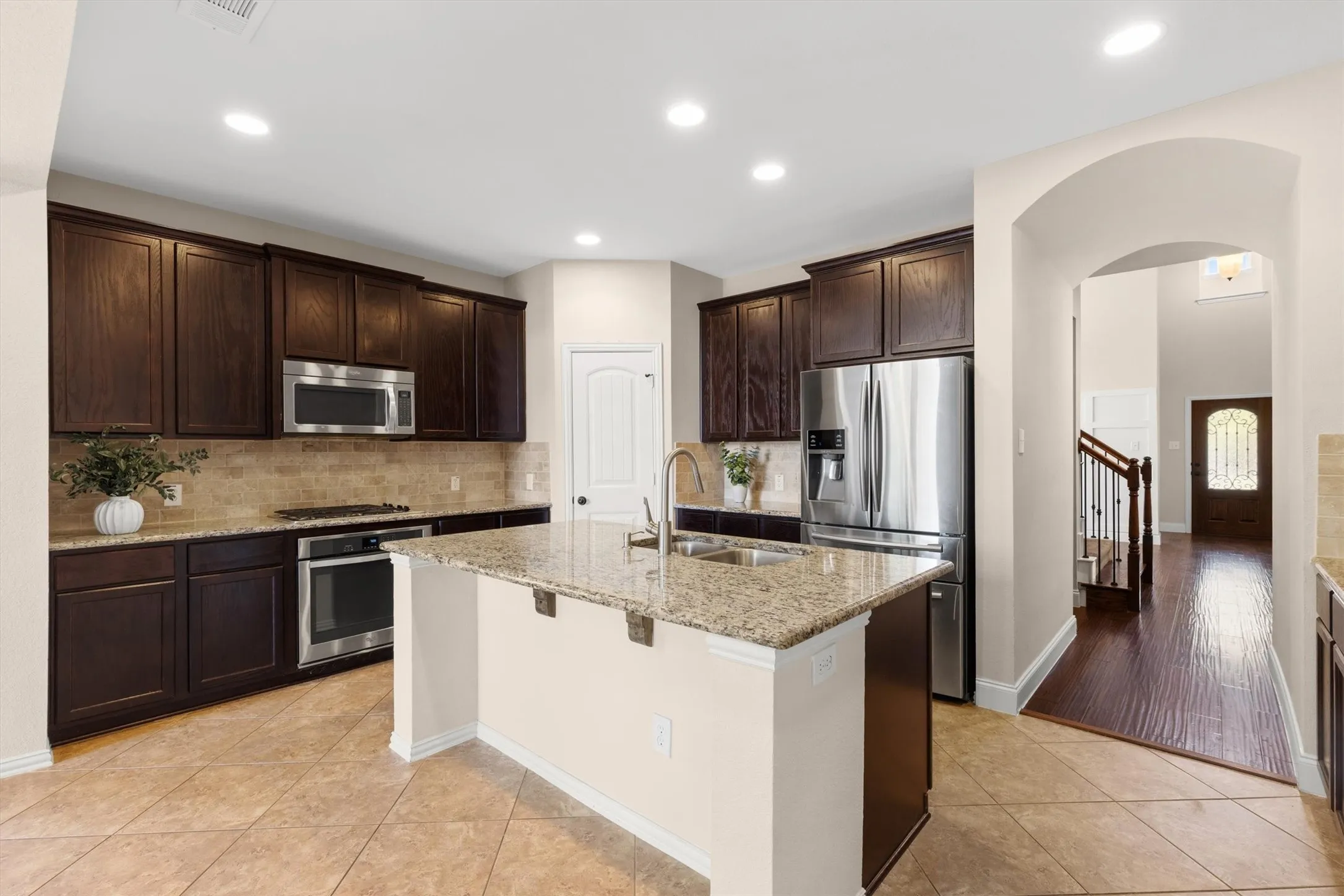 Kitchen featuring an island with granite countertops, dark wood cabinetry, and stainless steel appliances