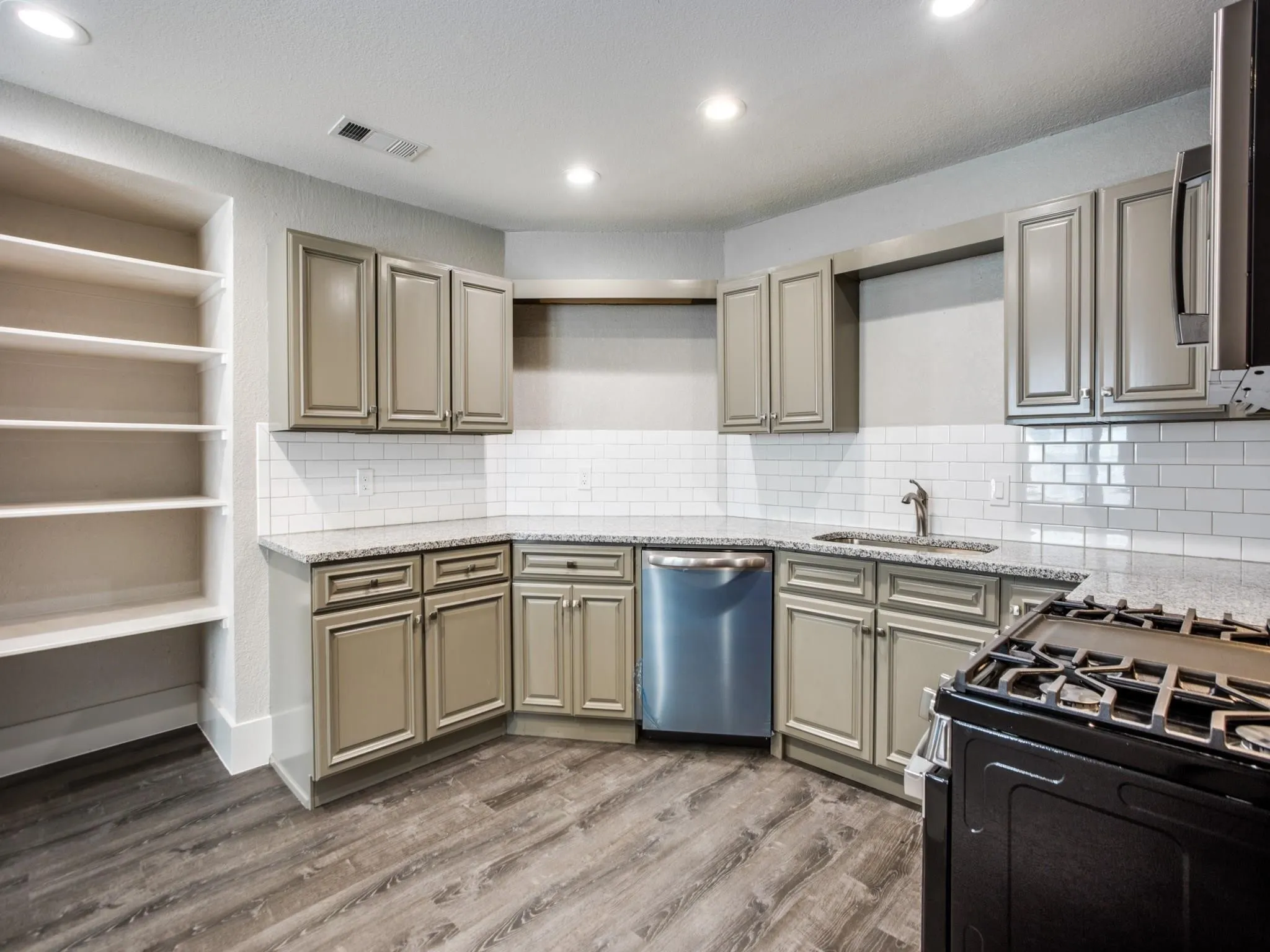 Kitchen featuring wood-finish flooring, recessed lighting, subway tile backsplash, light-toned cabinetry, and speckled countertops