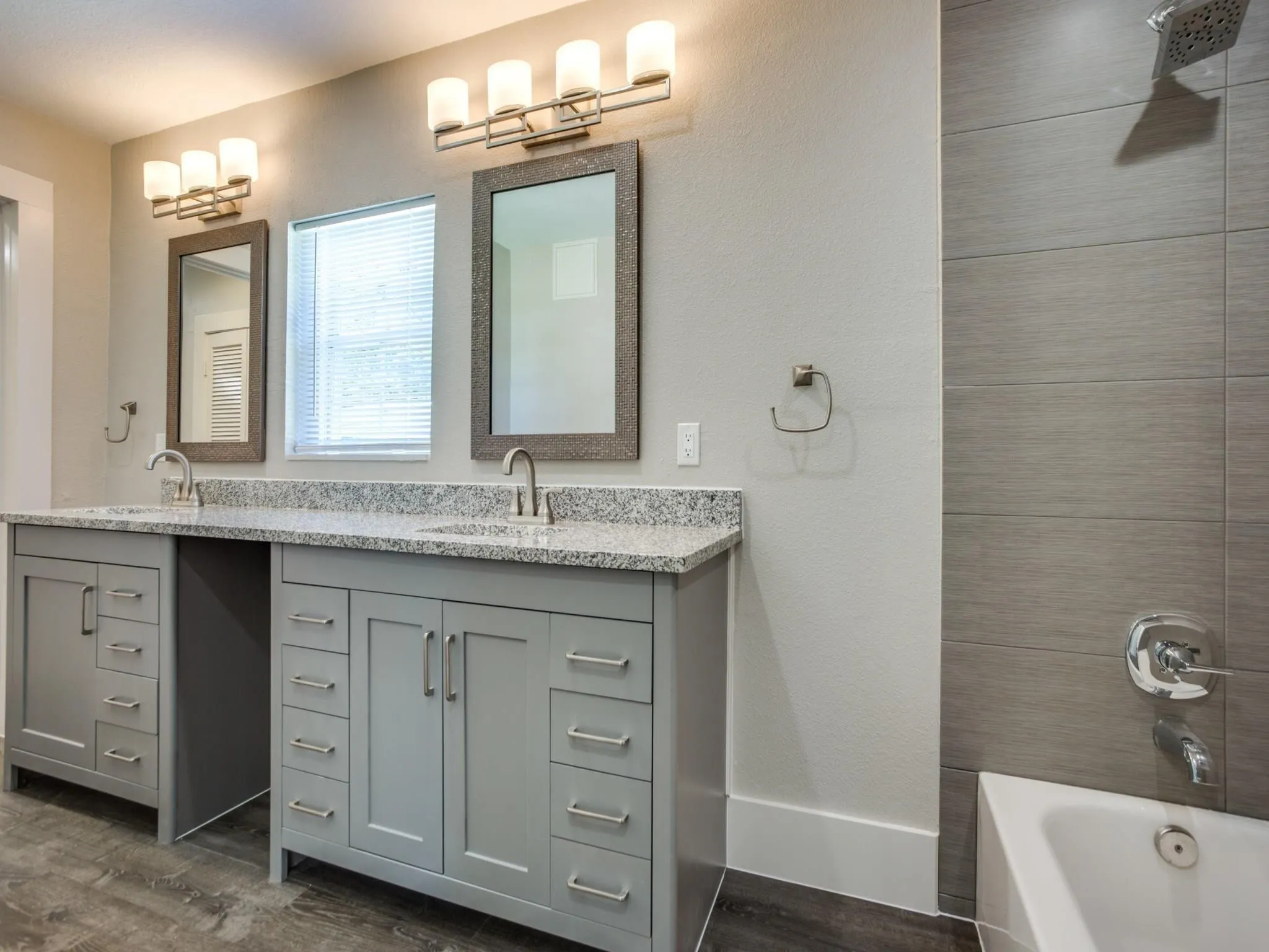 Bathroom featuring a dual vanity with light gray cabinetry and granite countertops