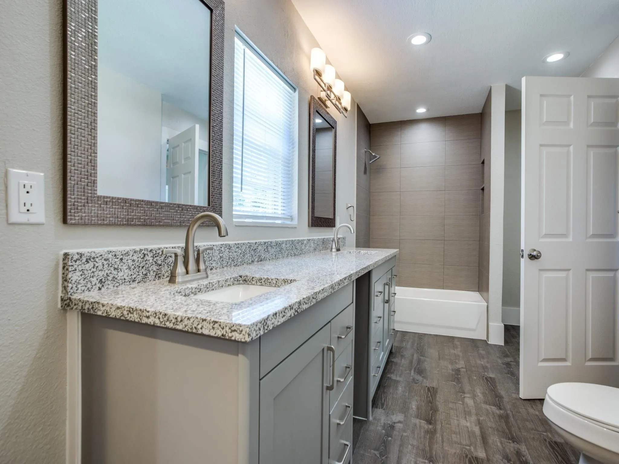 Bathroom featuring a double vanity with granite countertops, undermount sinks, and contemporary brushed nickel faucets