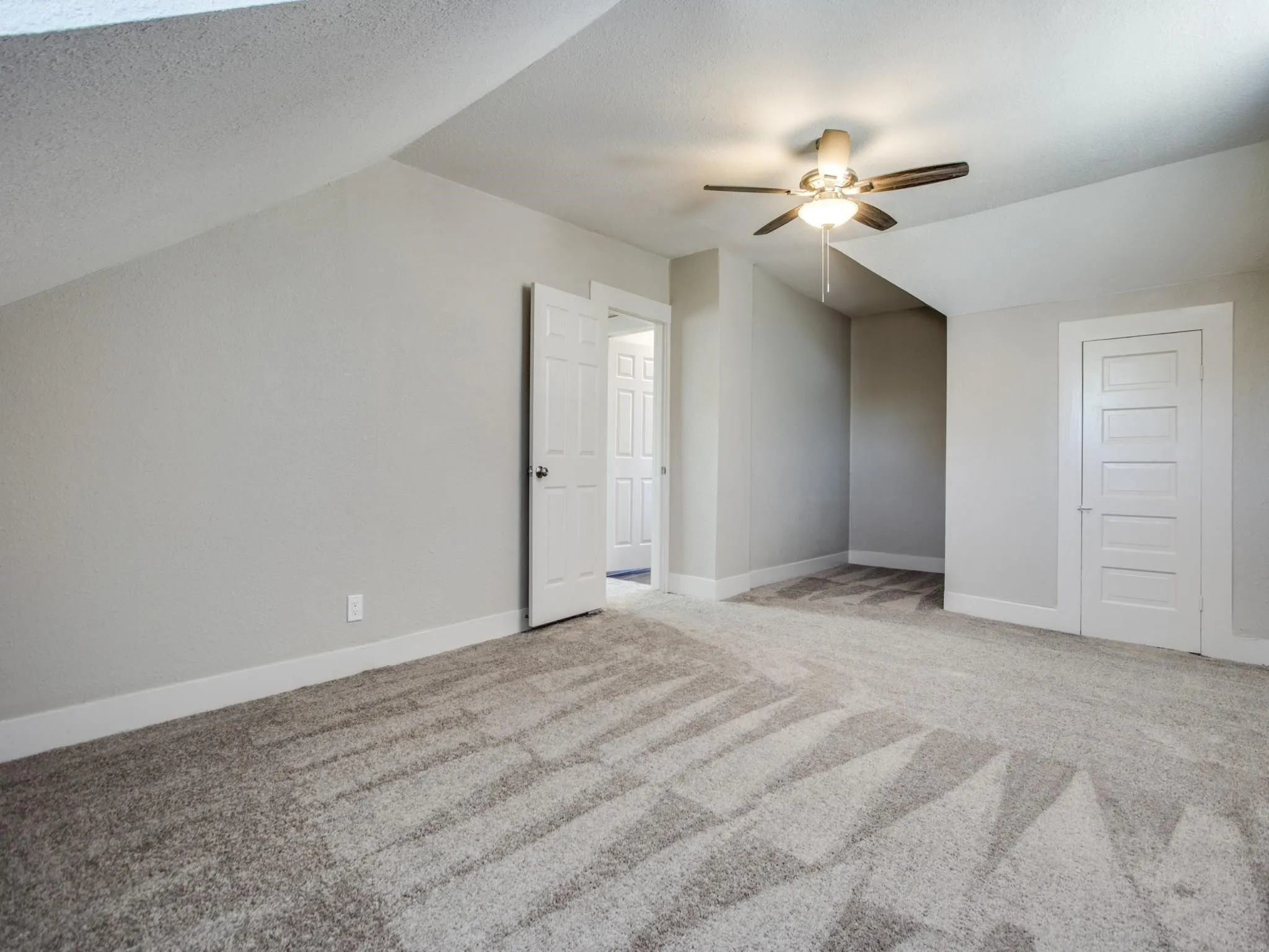 Carpeted room with a ceiling fan light fixture and white five-panel doors