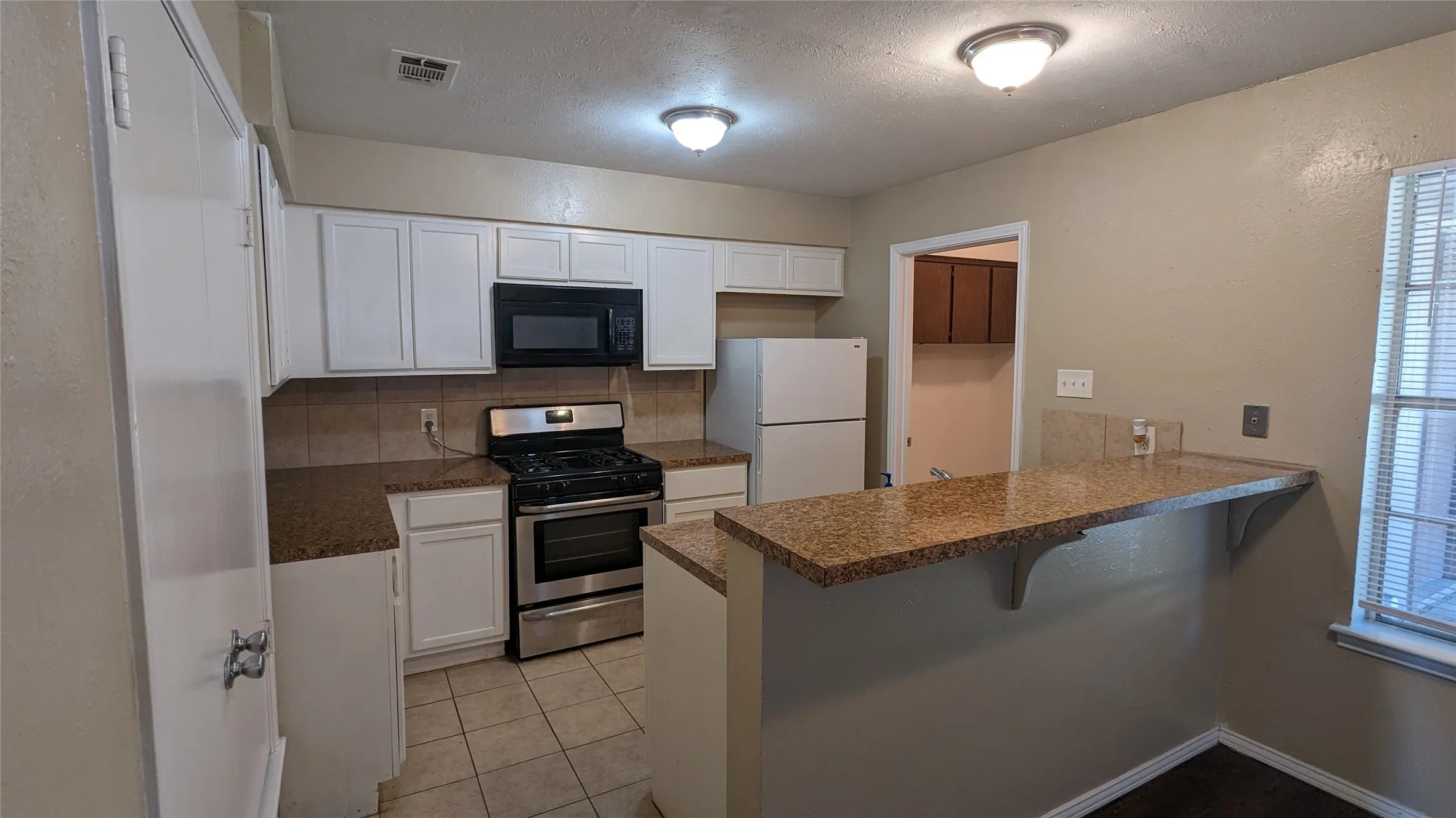 Kitchen featuring white cabinetry, granite-finish countertops, and tile flooring