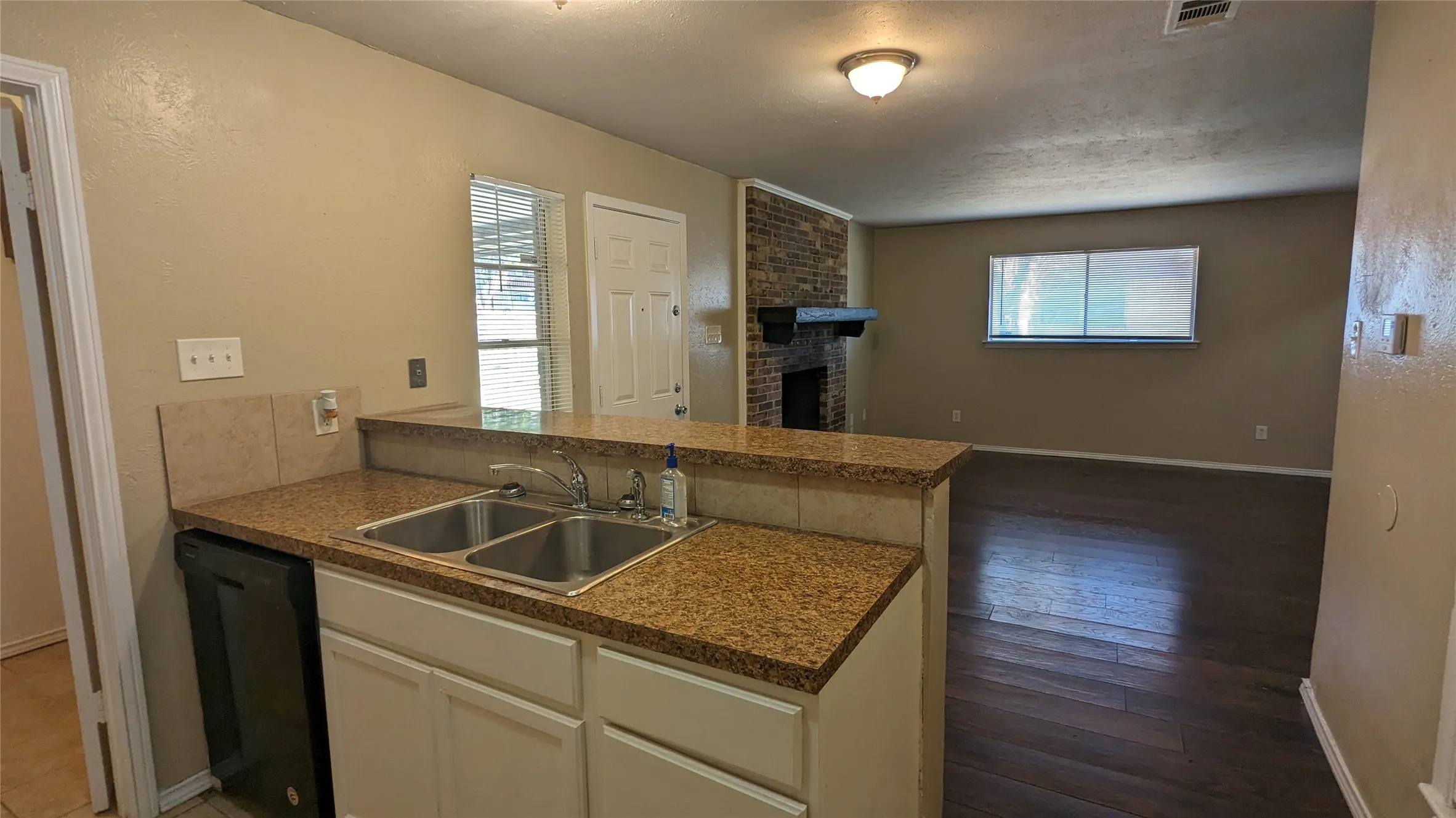 Kitchen with a double basin stainless steel sink, granite-style countertops, and white cabinetry