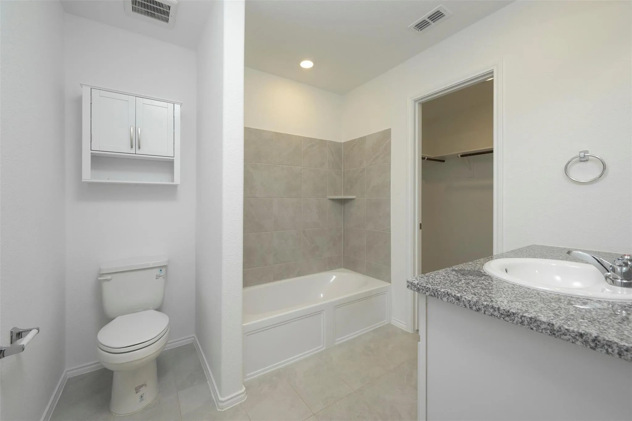 Full bathroom featuring tiled shower / bath combo, tile flooring, toilet, and vanity