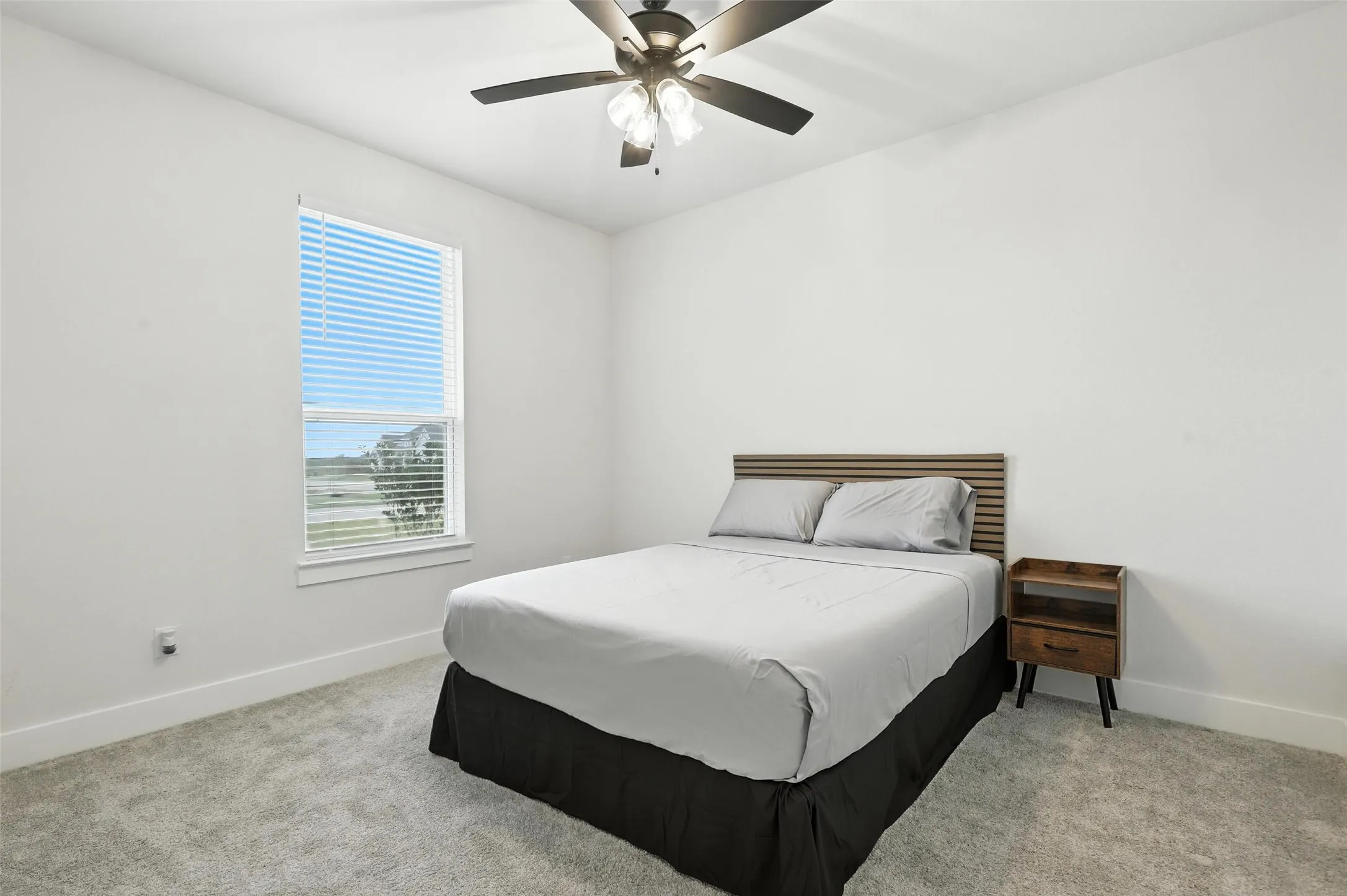Bedroom featuring a ceiling fan with integrated lighting, a large window with blinds, and light-colored carpeting