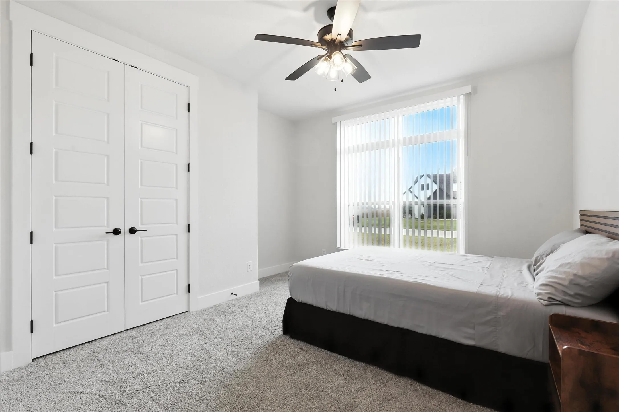 White paneled bi-fold closet doors with black hardware, complementing light gray carpeting