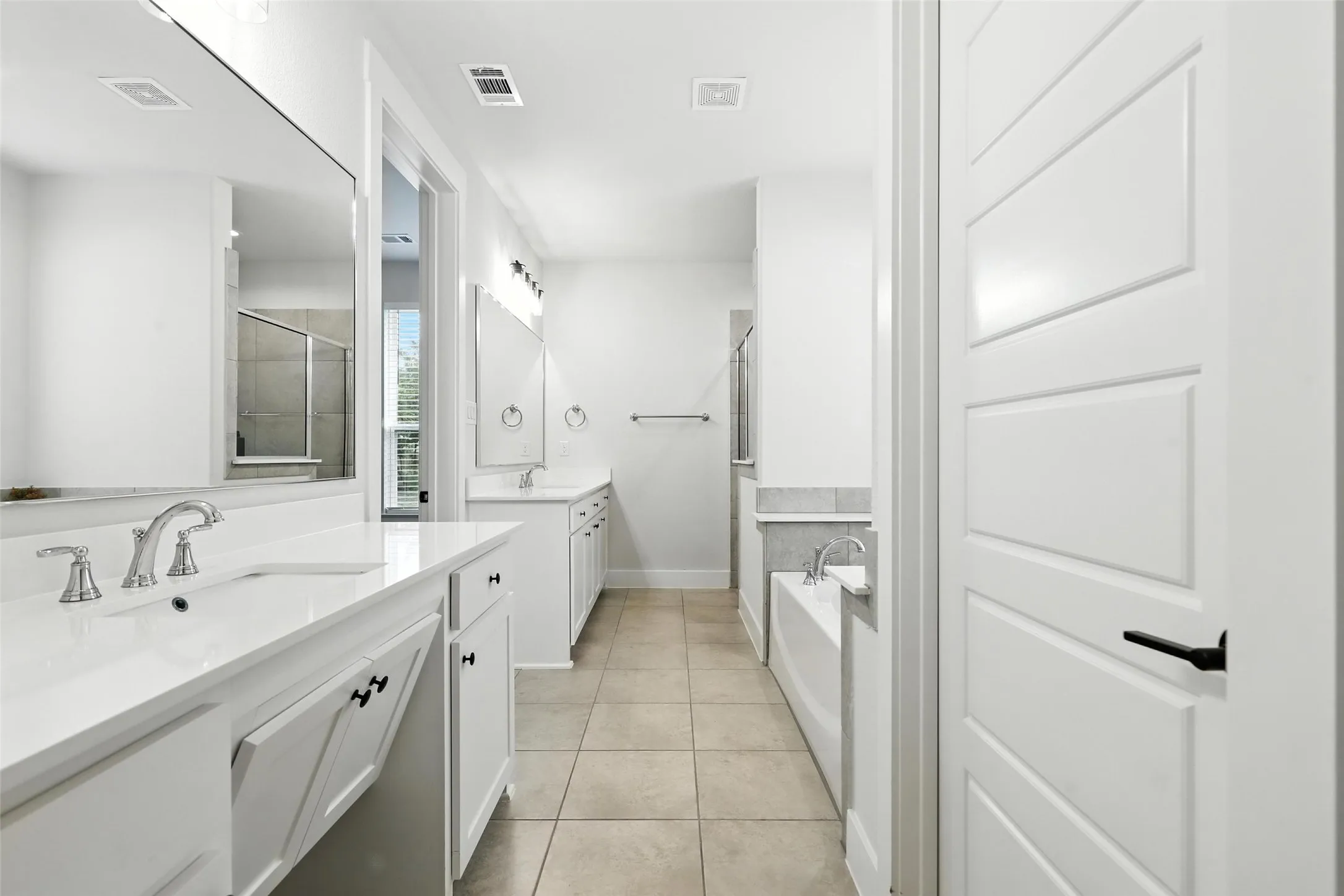 Bright bathroom featuring dual vanities with white countertops and chrome fixtures
