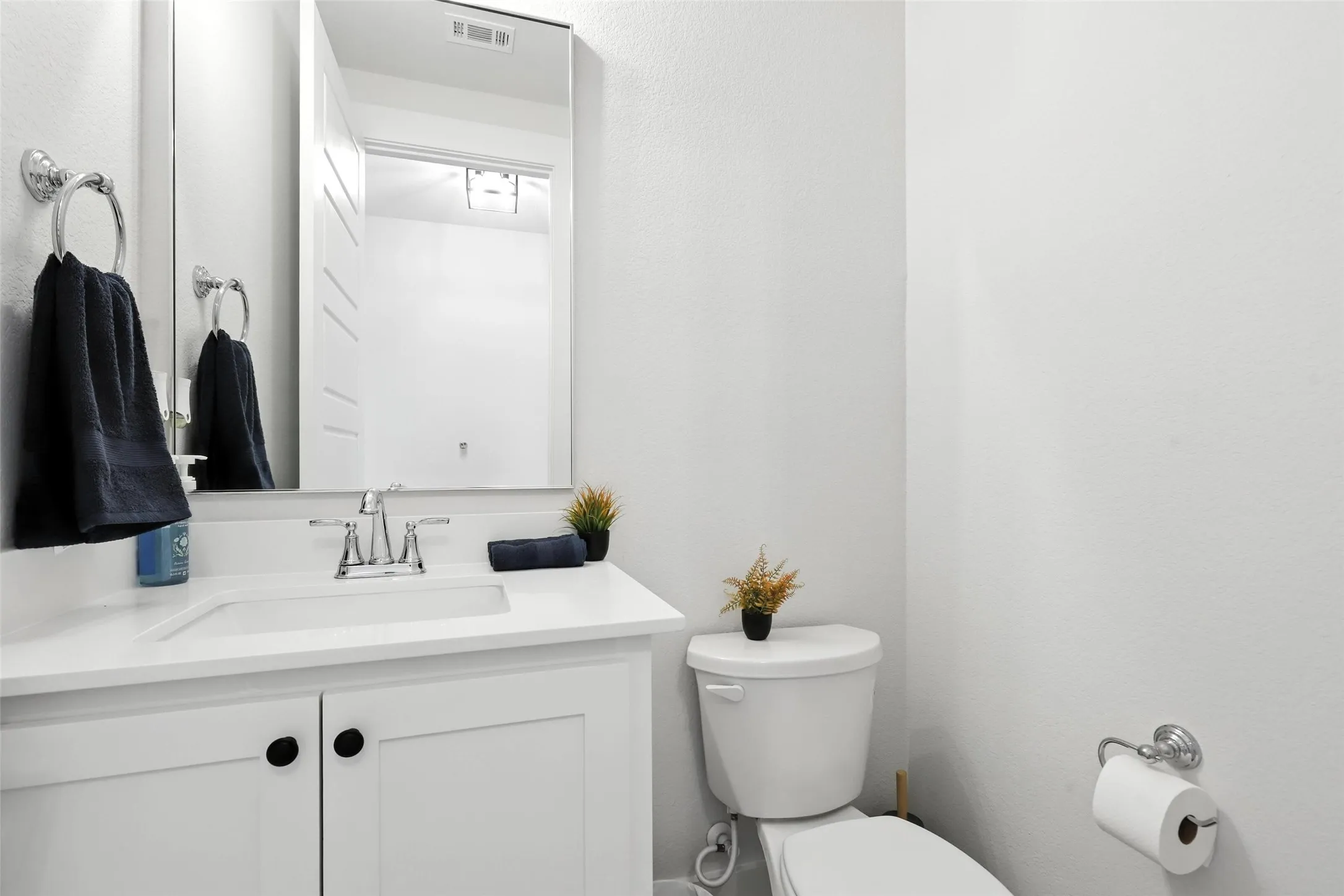 Bathroom featuring a white vanity with integrated sink, chrome faucet, and rectangular mirror
