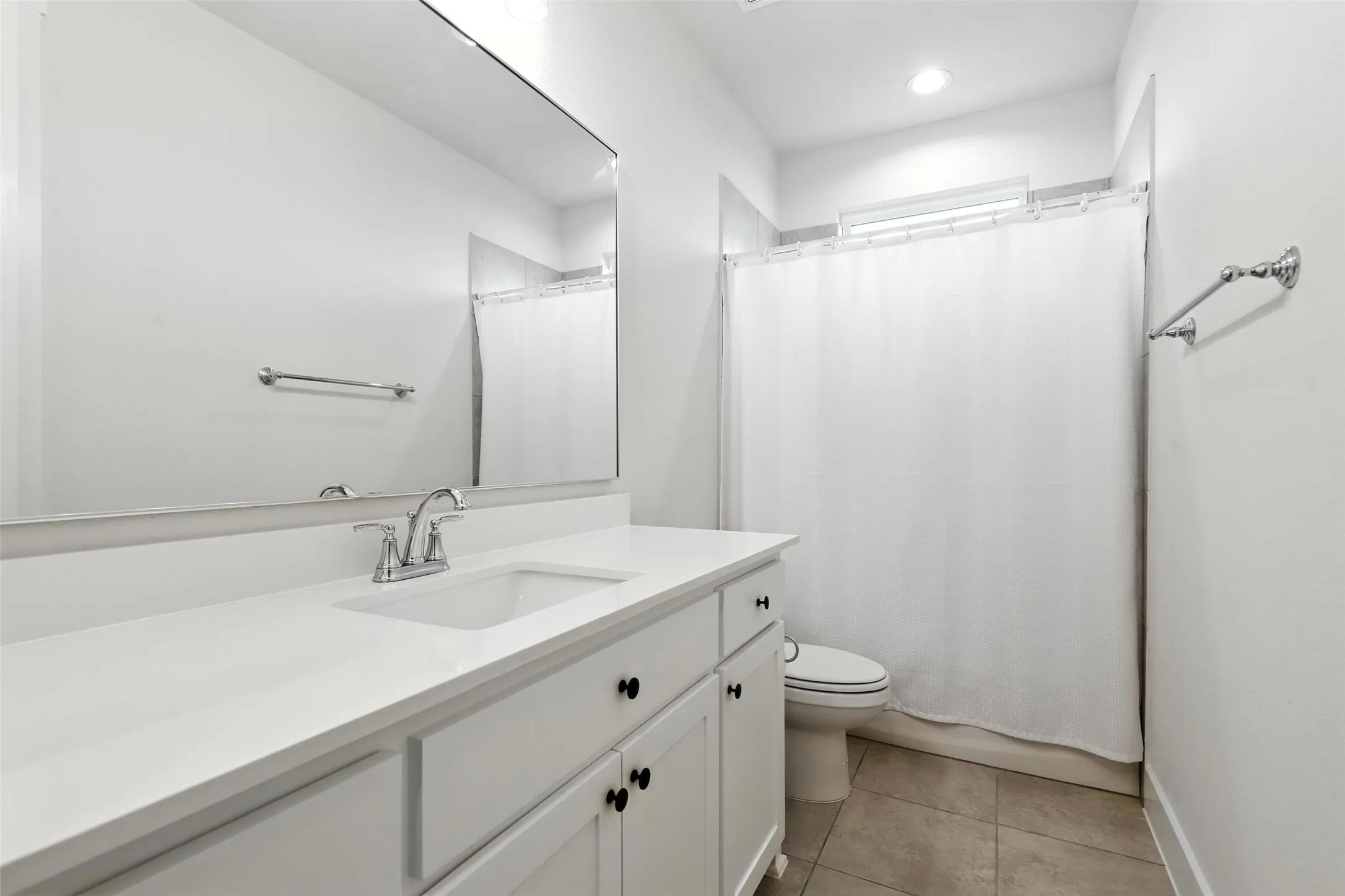 Bathroom featuring a white vanity with an integrated sink, chrome faucet, and matte black cabinet pulls